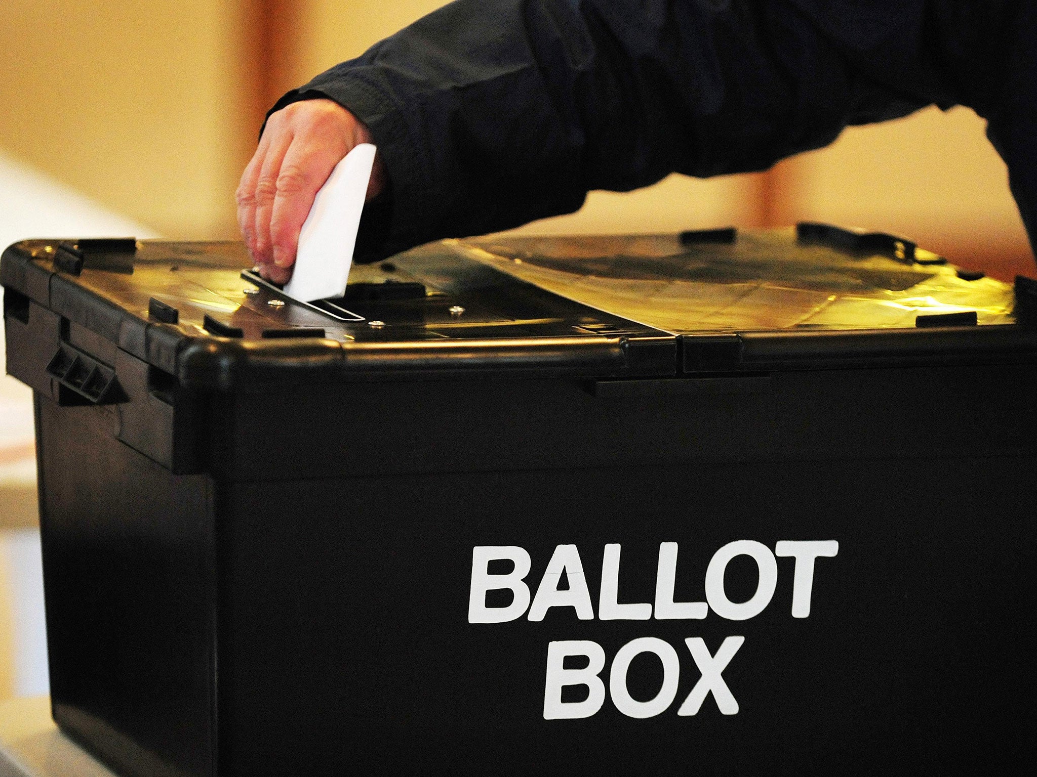 A voter placing a ballot paper in the box at a polling station