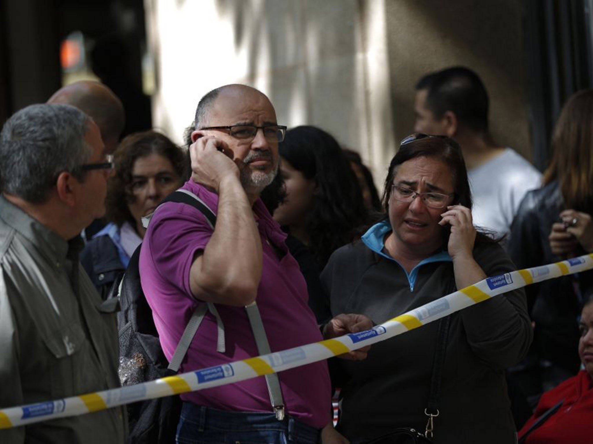 People stand behind a police cordon outside the school in Barcelona following the attack