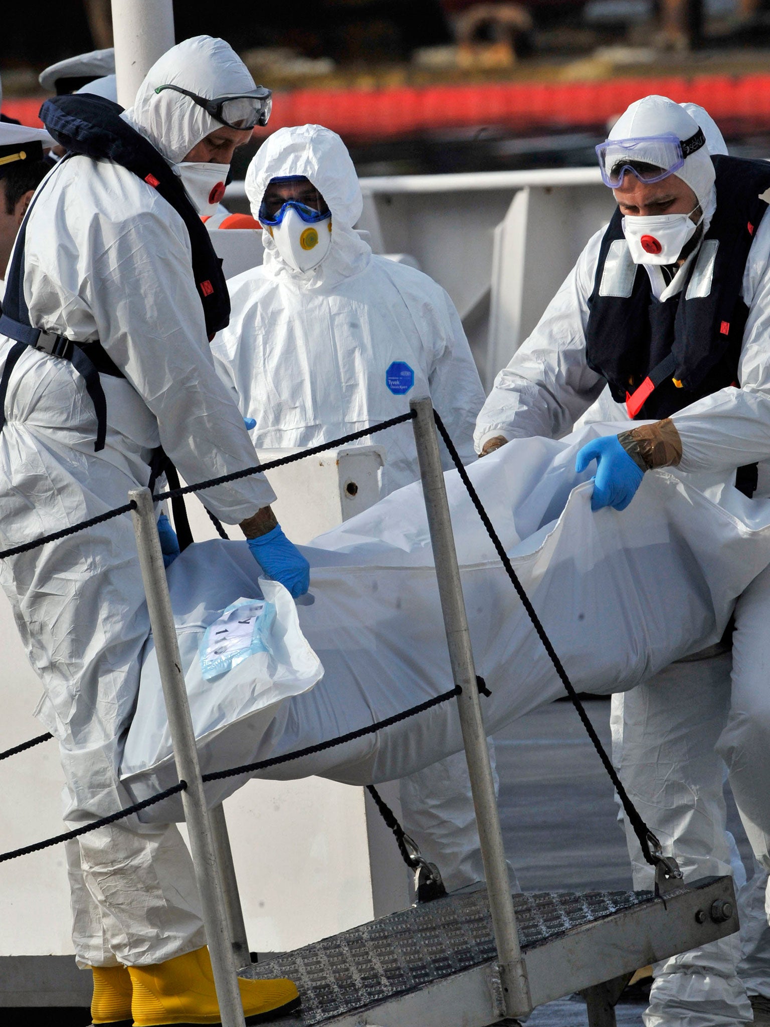 Italian Coast Guard officers disembark the body of a dead migrant