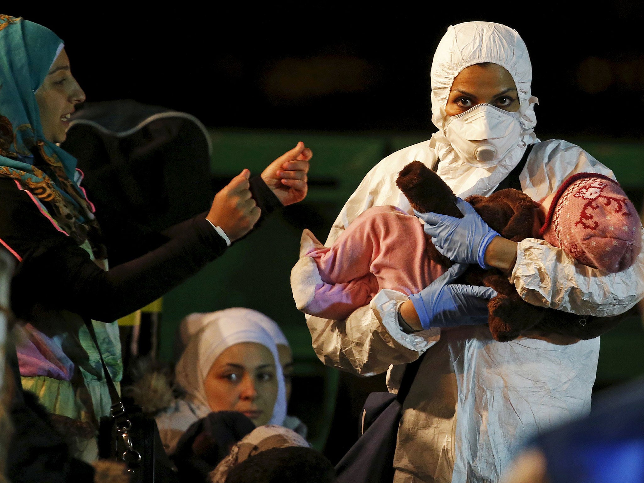 A child is carried by a rescue worker as he arrives with migrants on the boat at the Sicilian harbor of Pozzallo