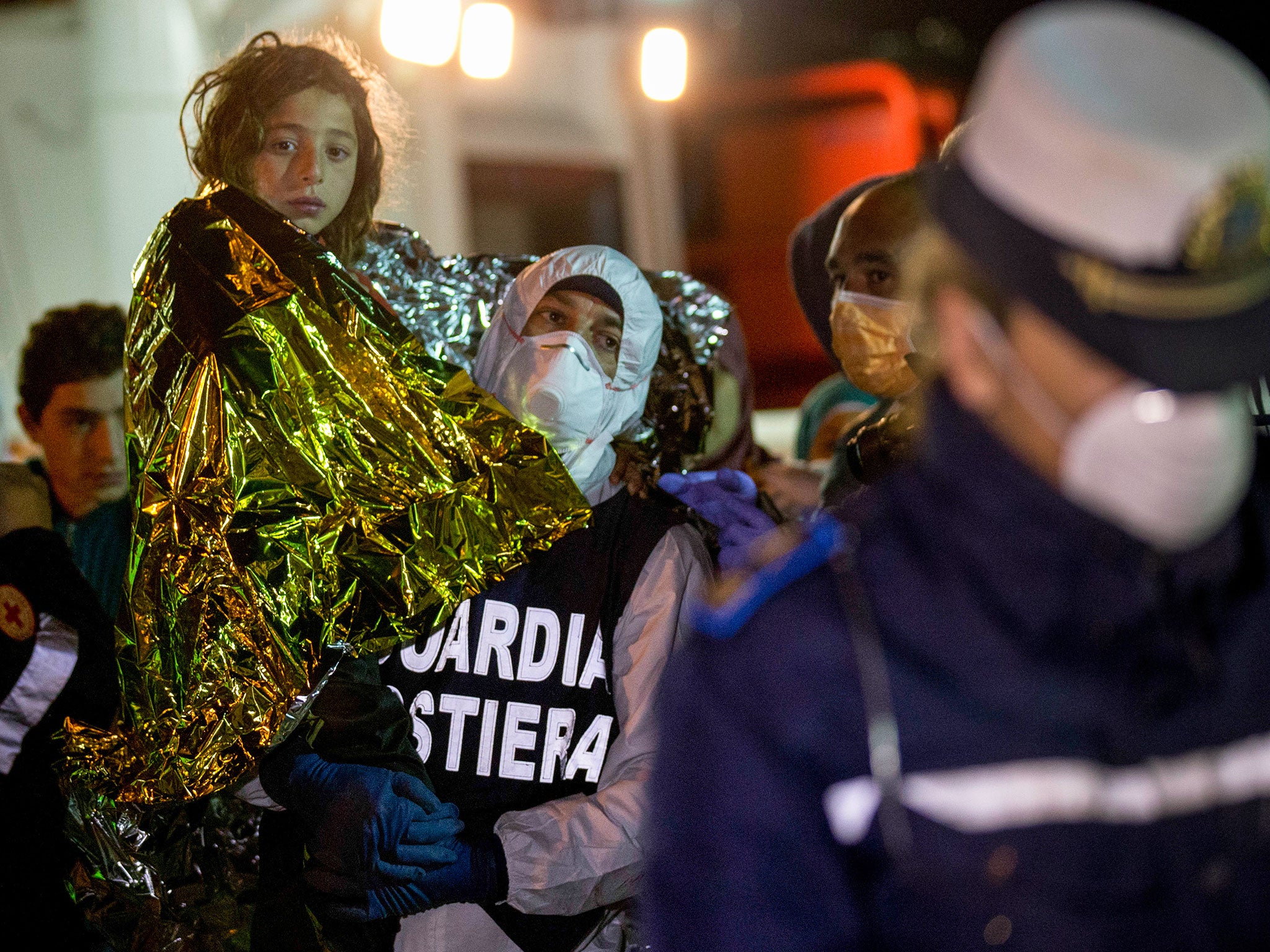 A migrant is helped disembark in the Sicilian harbor of Pozzallo, Italy