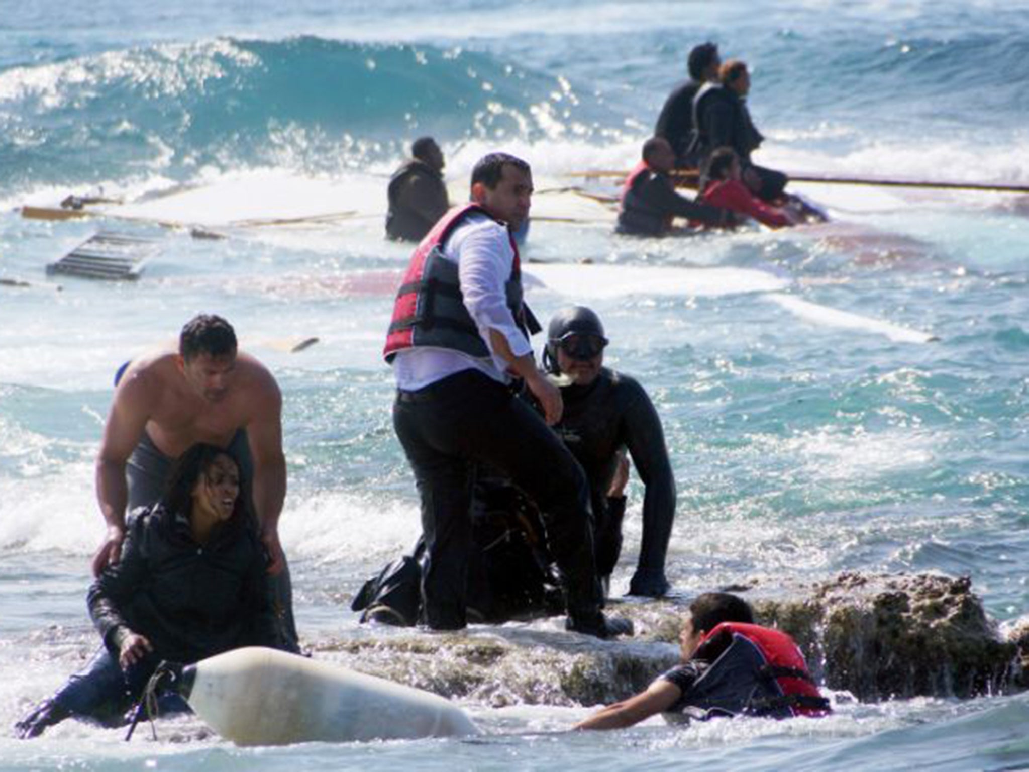 A man rescues an migrant from the Aegean sea; some 80 per cent of those arriving illegally in Europe have done so only after paying smugglers to facilitate some or all of their passage