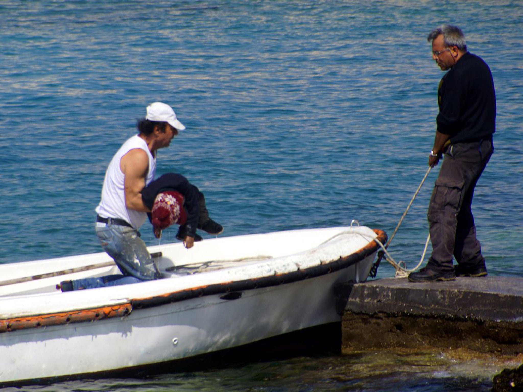 The body of a dead child is recovered off the coast of Rhodes. People smuggling is an industry where demand exceeds supply and the seller does not care greatly if the customer reaches their destination or not (AP)