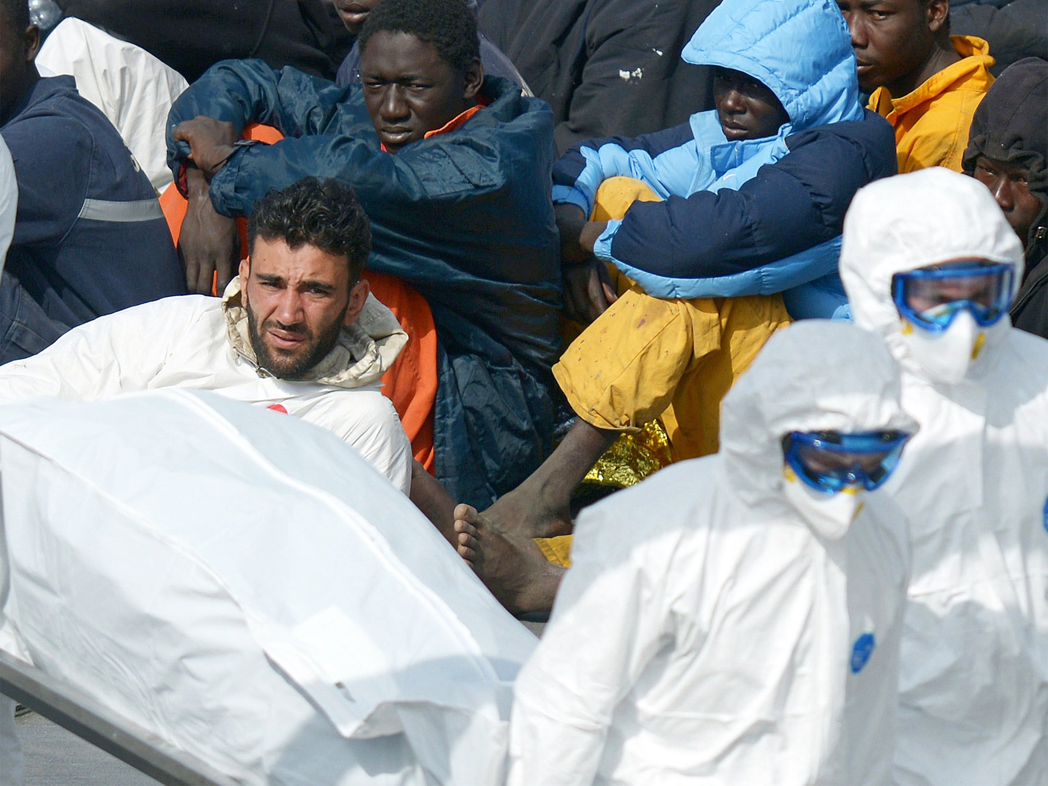 Mohammed Ali Malek, surrounded by some of his surviving ‘cargo’ of migrants after their rescue off Libya, watches rescuers carry a body from an Italian Coast Guard vessel in Malta (Getty)