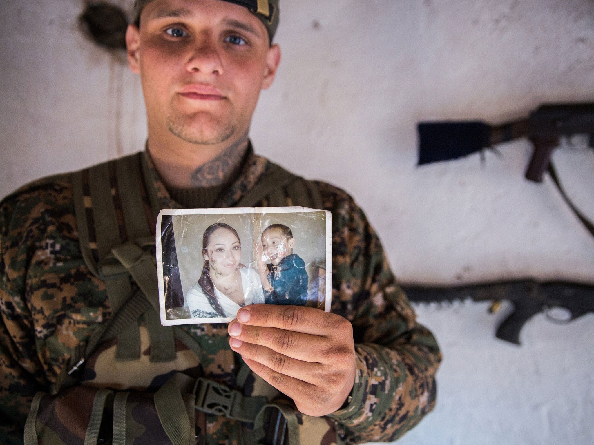 A 26-year old from the US, nick-named by Kurdish fighters as Hewal Dilsad, shows a picture of his wife and son in the town of Tal Tamr