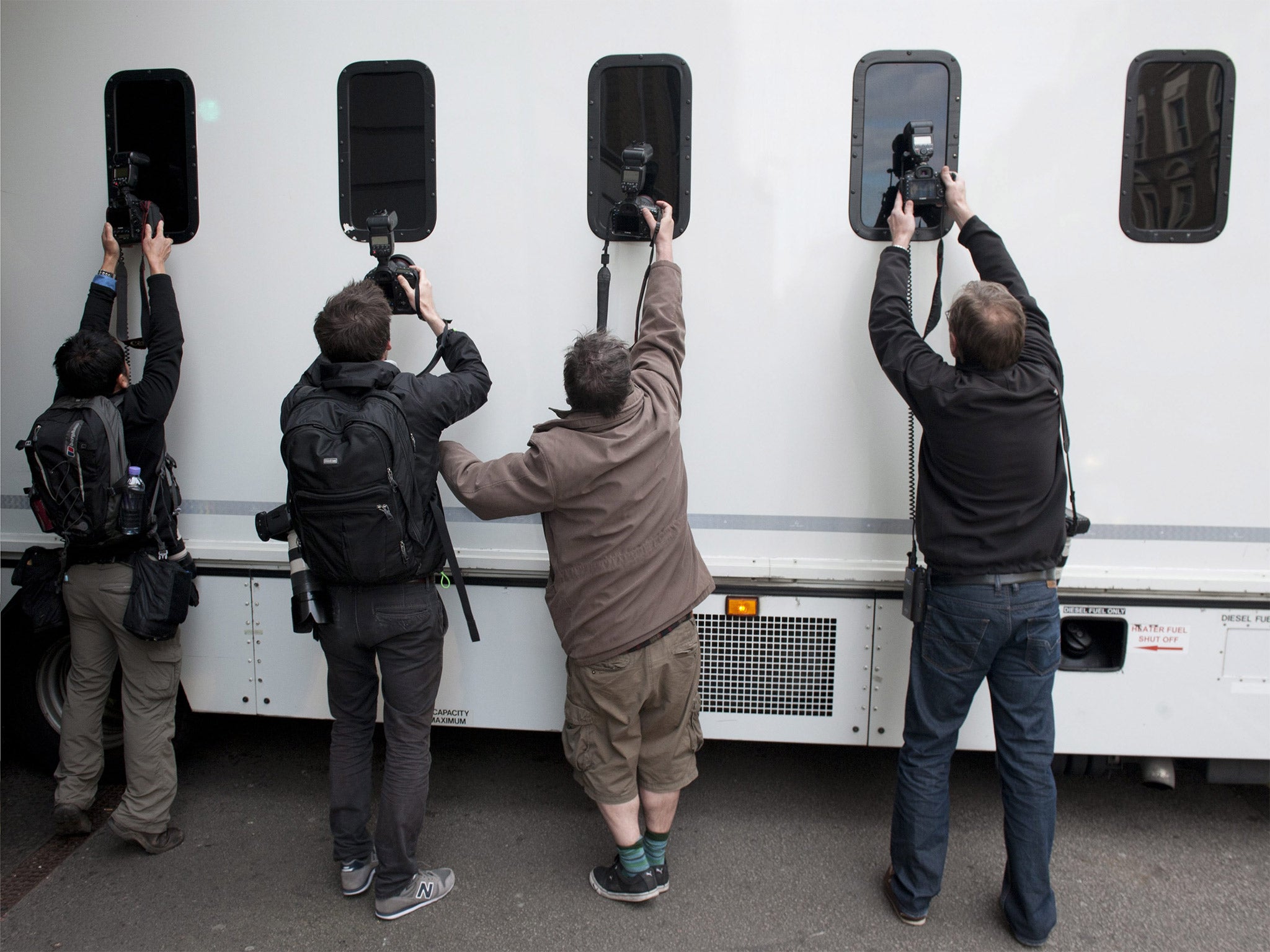 Photographers try to take photos through the windows of a prison van transporting Navinder Singh Sarao, as it leaves Westminster Magistrates court