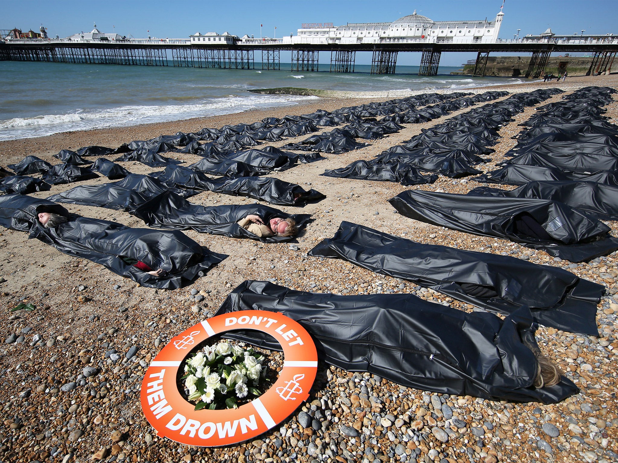 Amnesty International volunteers lie in 200 body bags on Brighton beach to highlight the migrant crisis in the Mediterranean (Getty)