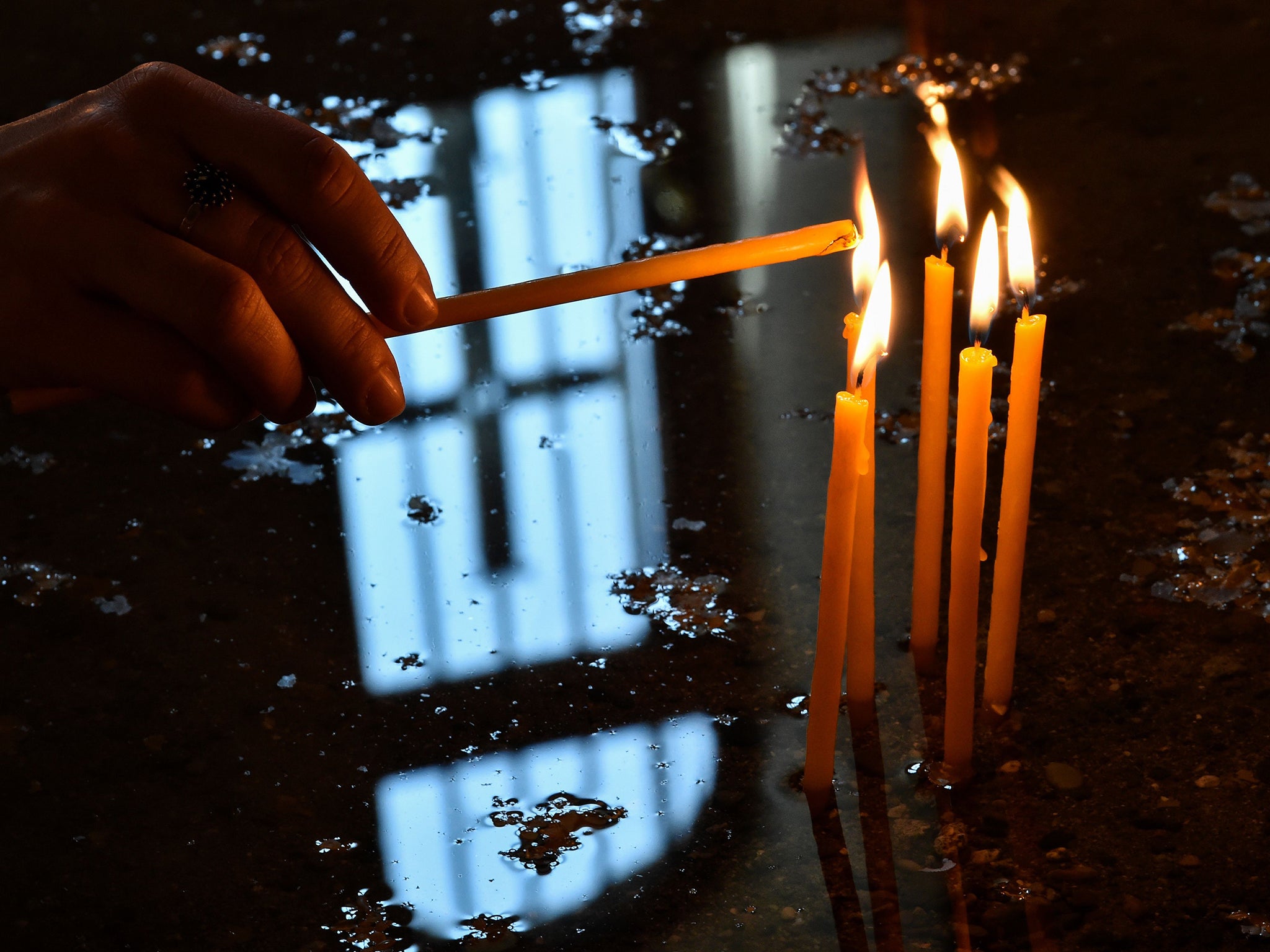 A woman lights candle in Etchmiadzin as Armenians prepare to commemorate a hundred years since 1.5 million of their kin were massacred by Ottoman forces