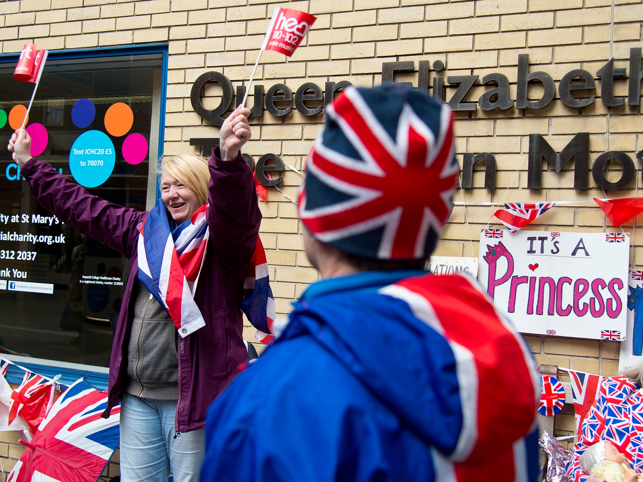 A well wisher waves flags as she waits outside the hospital for the impending royal birth