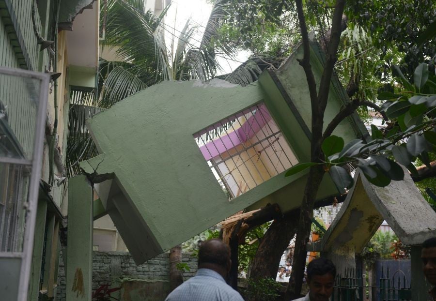 Indian bystanders look at a collapsed house following an earthquake, in Siliguri