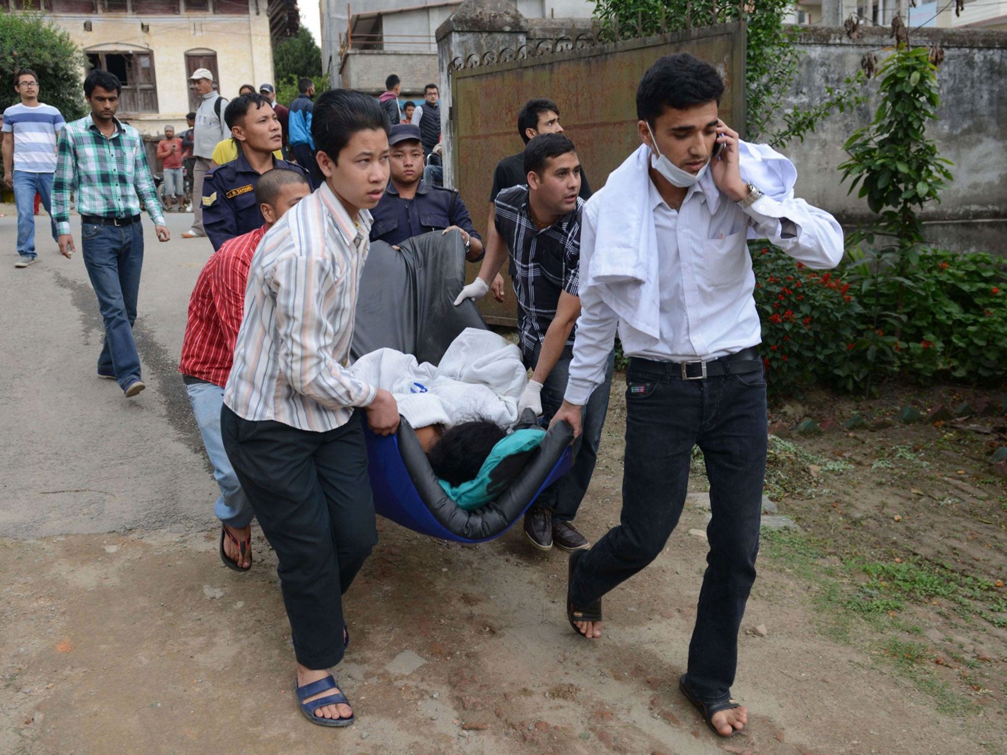 Nepalese health workers carry injured people into an open area following the earthquake