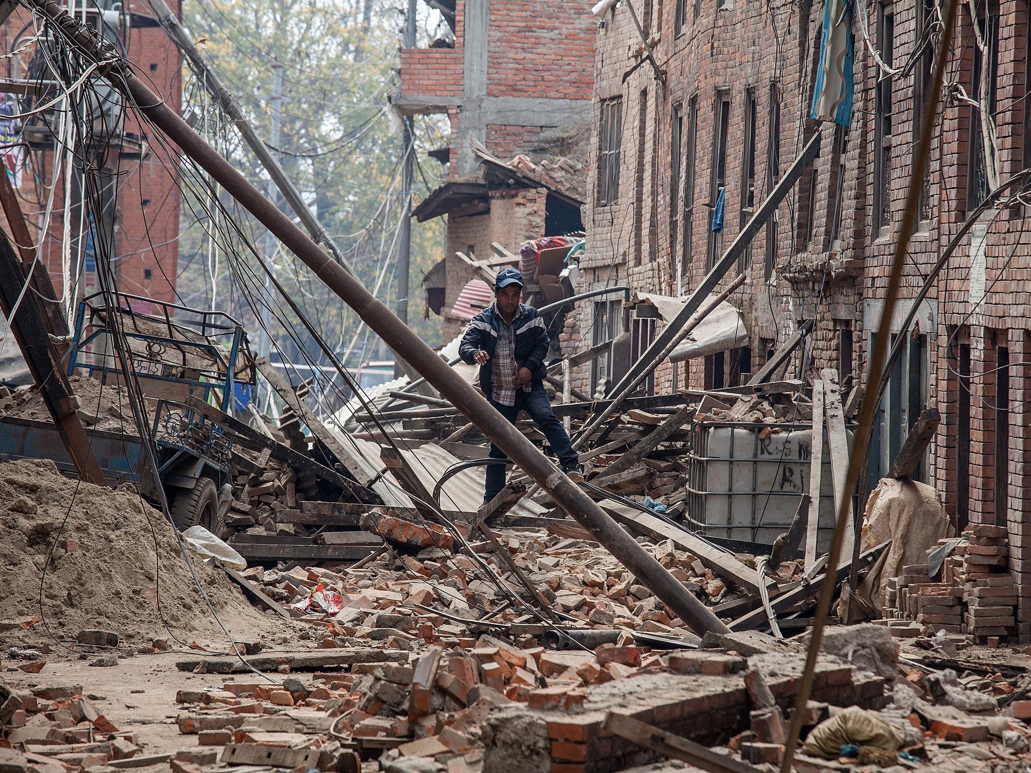 A man runs down a street covered in debris after buildings collapsed under the force of the earthquake