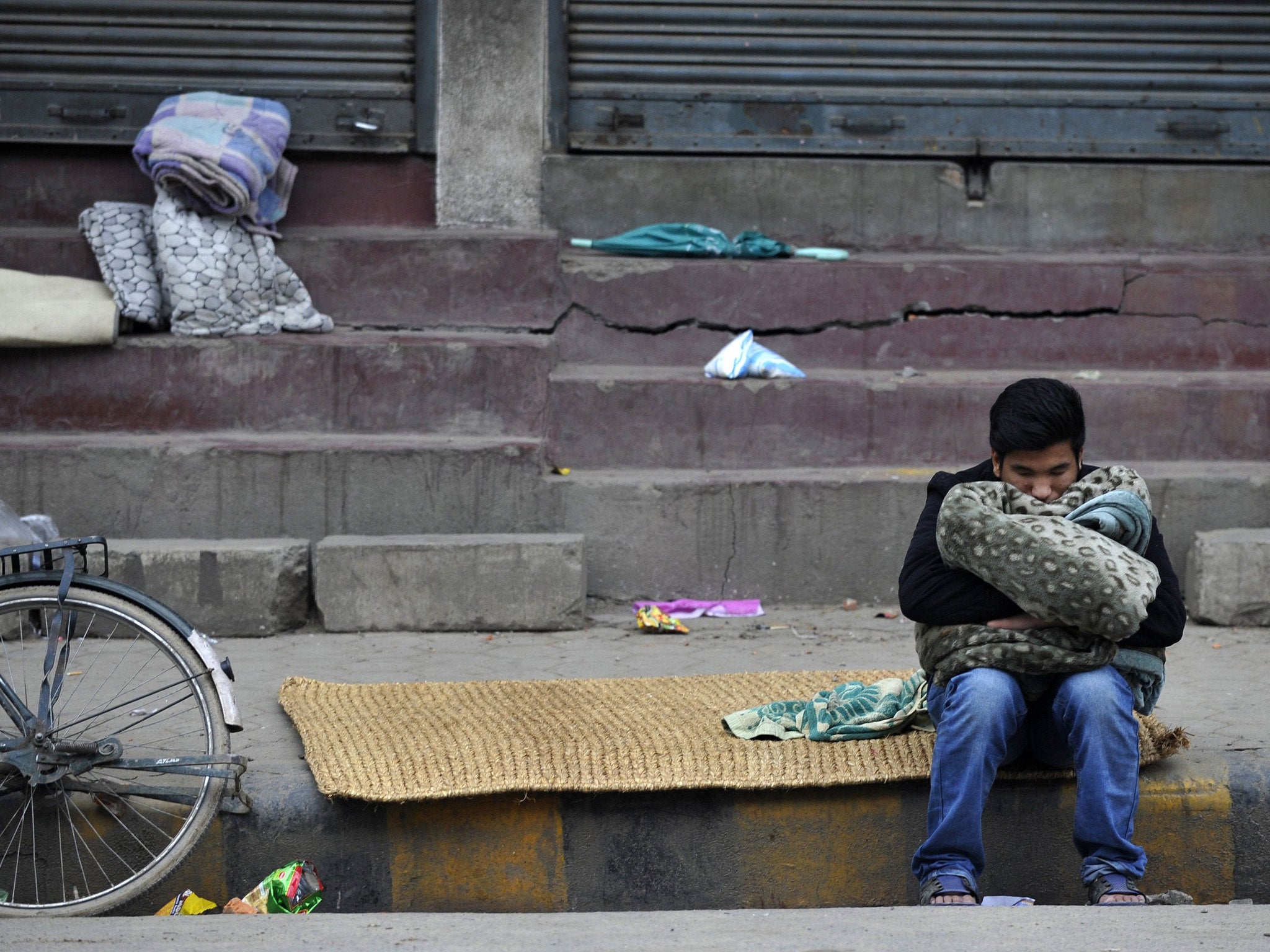 A Nepalese resident naps by the roadside in the aftermath of the earthquake