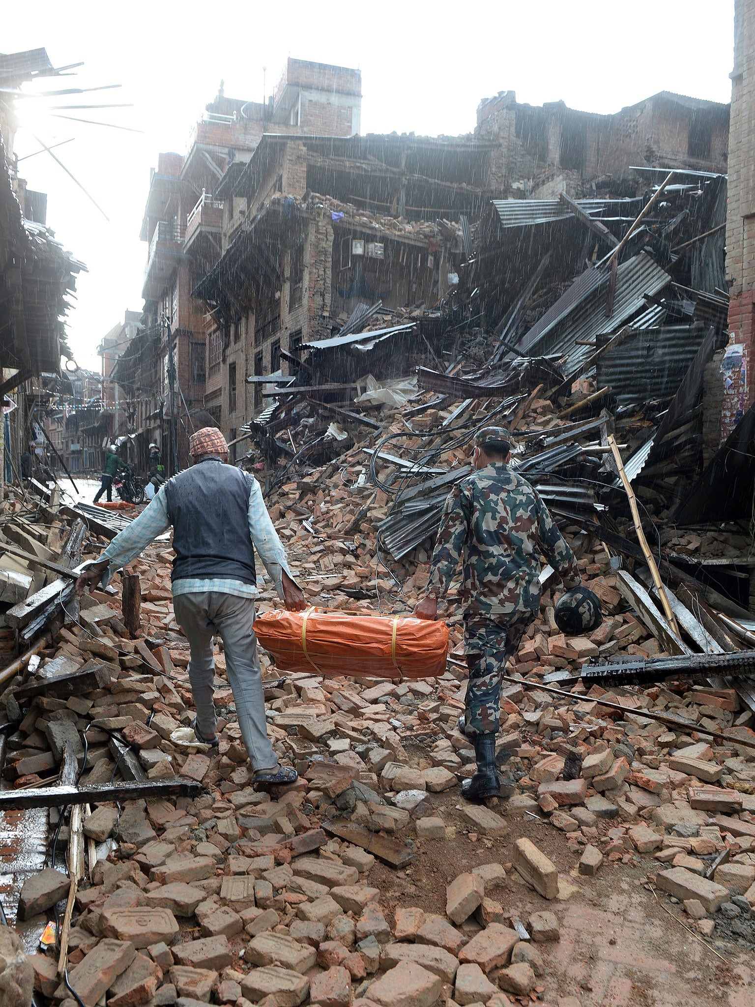 A Nepalese volunteer and member of the security forces carry tents to be distributed in Bhaktapur on the outskirts of Kathmanduon