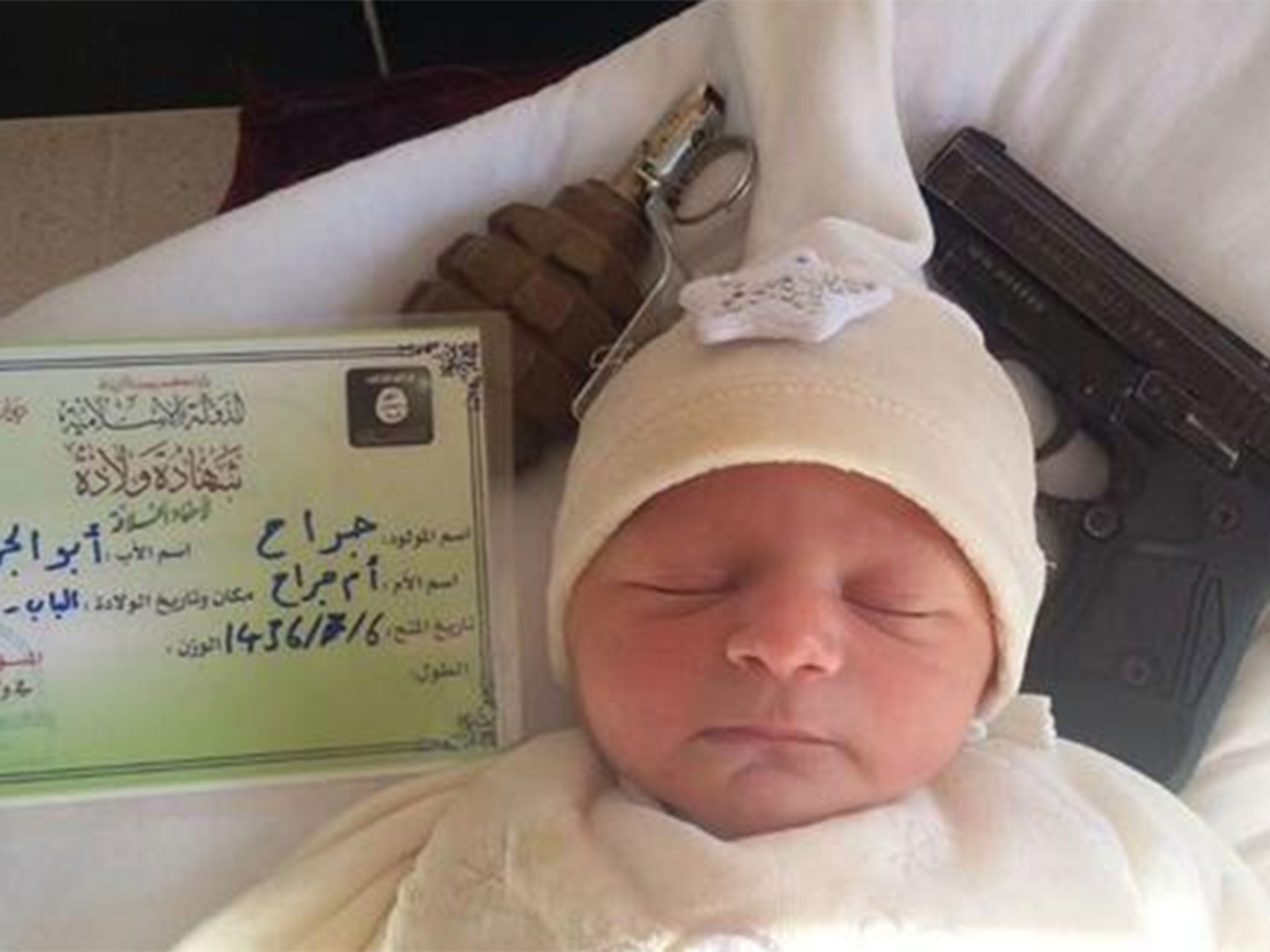 A baby lies beside weapons and a birth a so-called Islamic State birth certificate