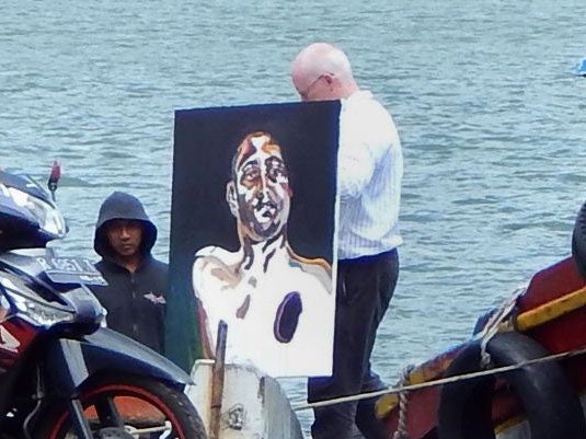 The lawyer for Australian death row inmates Myuran Sukumaran carries a painting after visiting Indonesia's Nusakambangan island on April 26