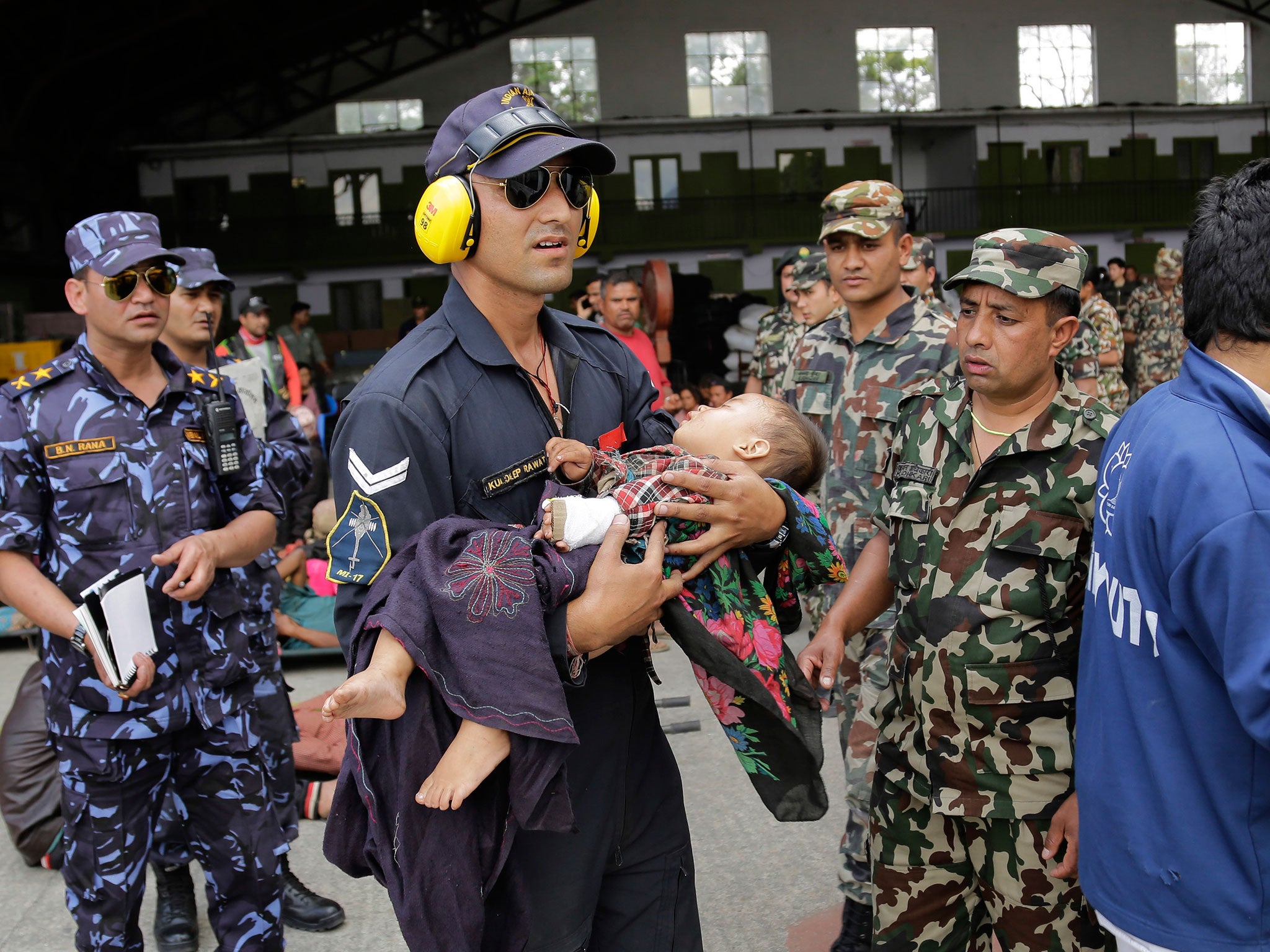 An Indian Air Force person carries a Nepalese child