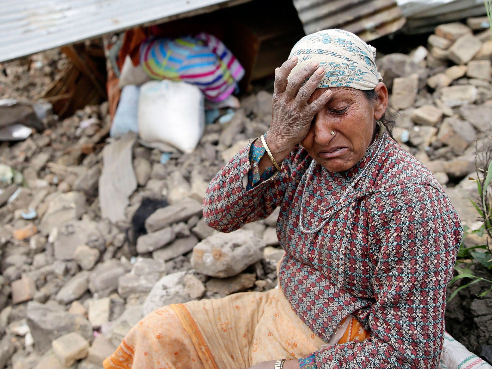 An elderly woman mourns in front of her destroyed home in the Kumalpur village