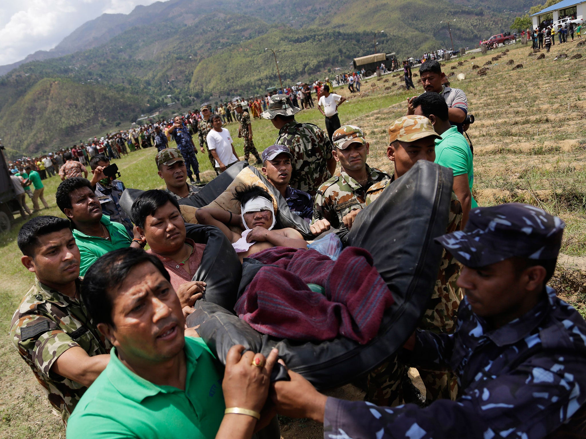 Nepalese soldiers carry a wounded man on a makeshift stretcher to a waiting Indian air force helicopter