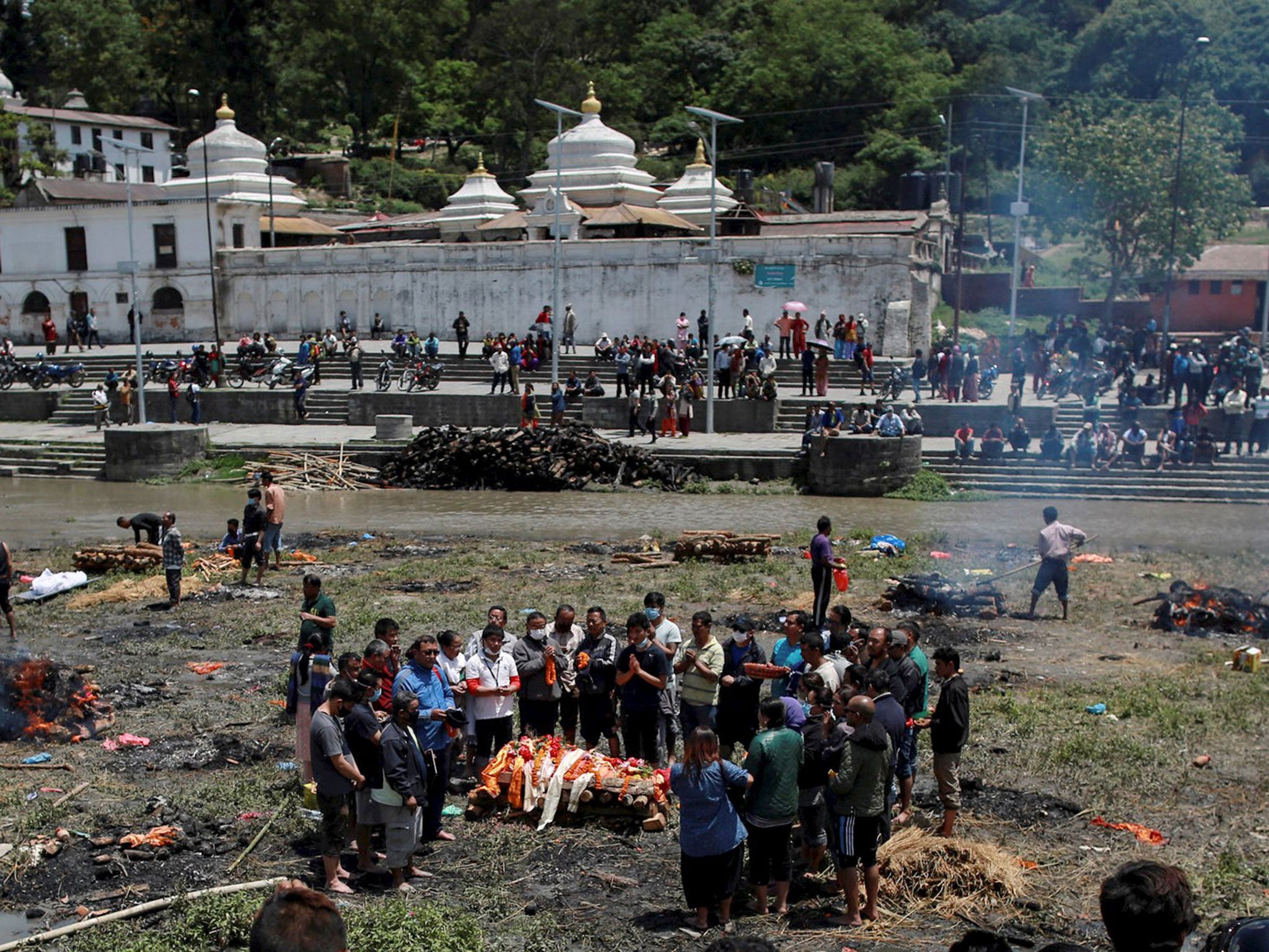 People pray before cremating the body of a victim of the earthquake