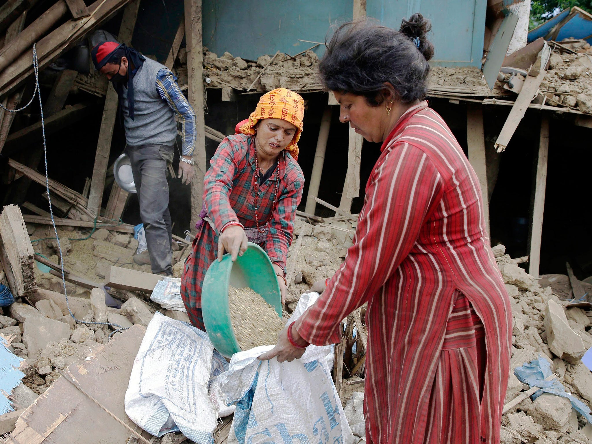 Earthquake victims collect belongings and salvage food items from a destroyed building