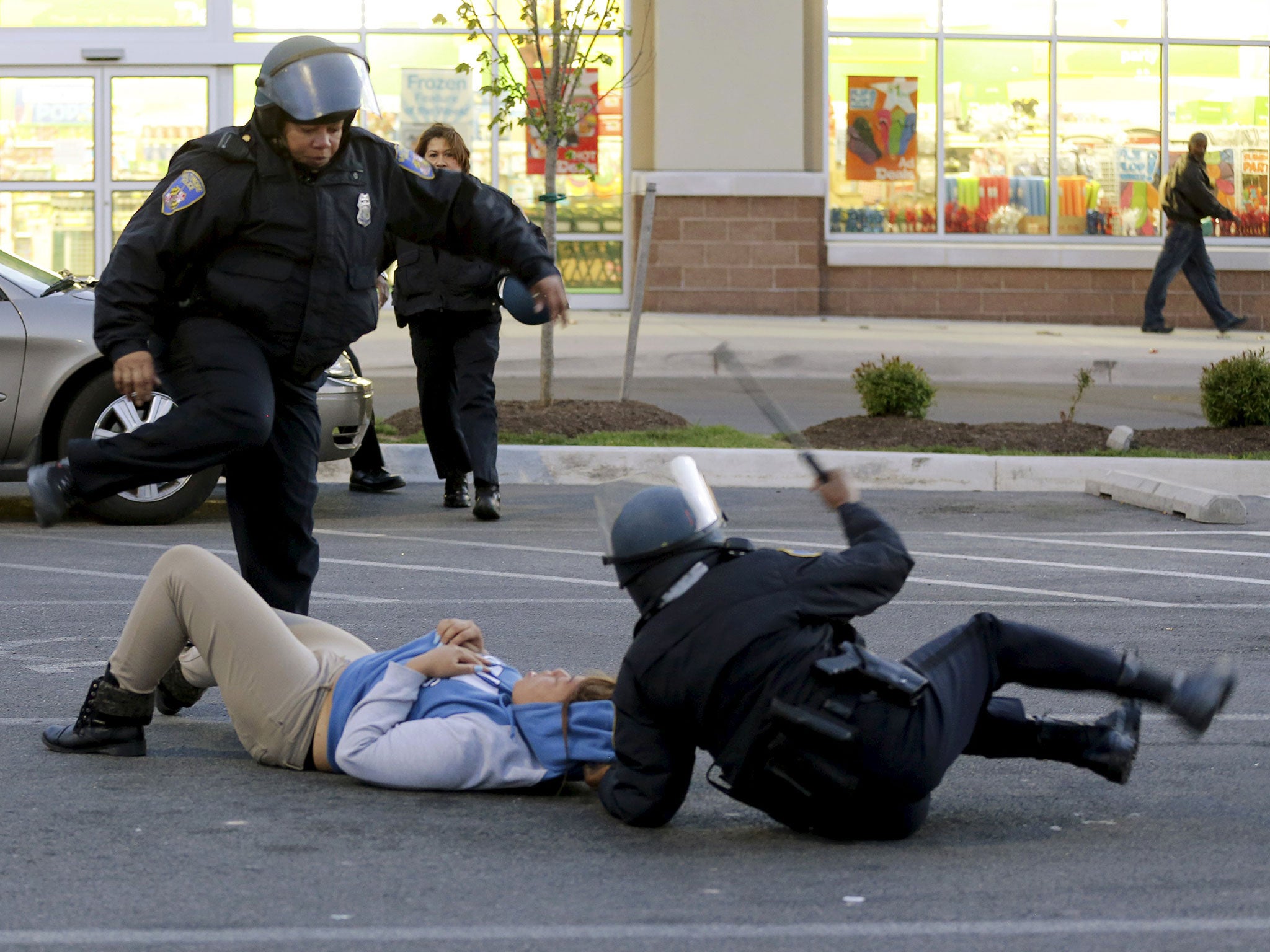 Baltimore police officers tackle and arrest looters after they emerged from a "Deals" store