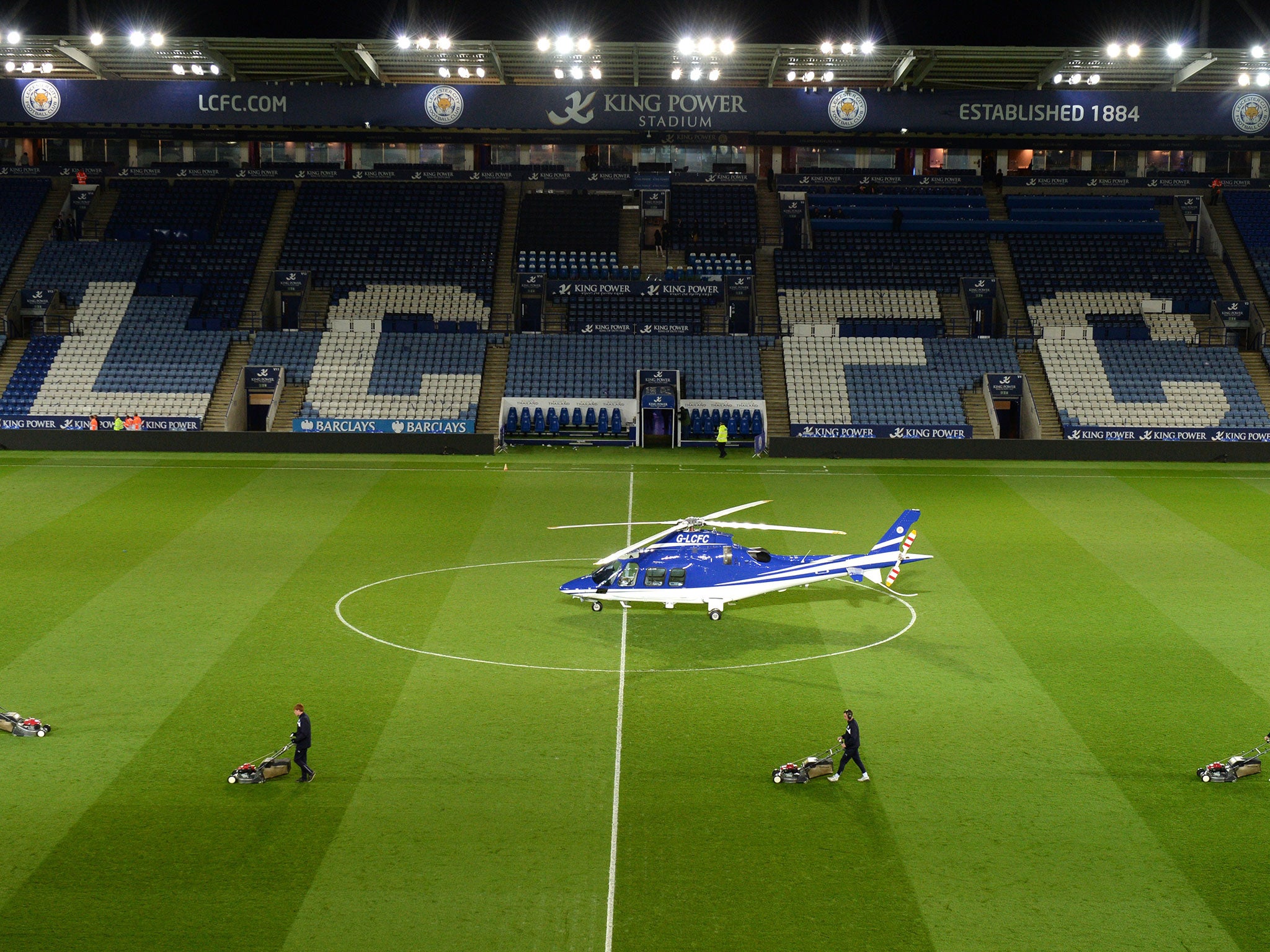 Leicester's ground staff work on the pitch despite the presence of the helicopter