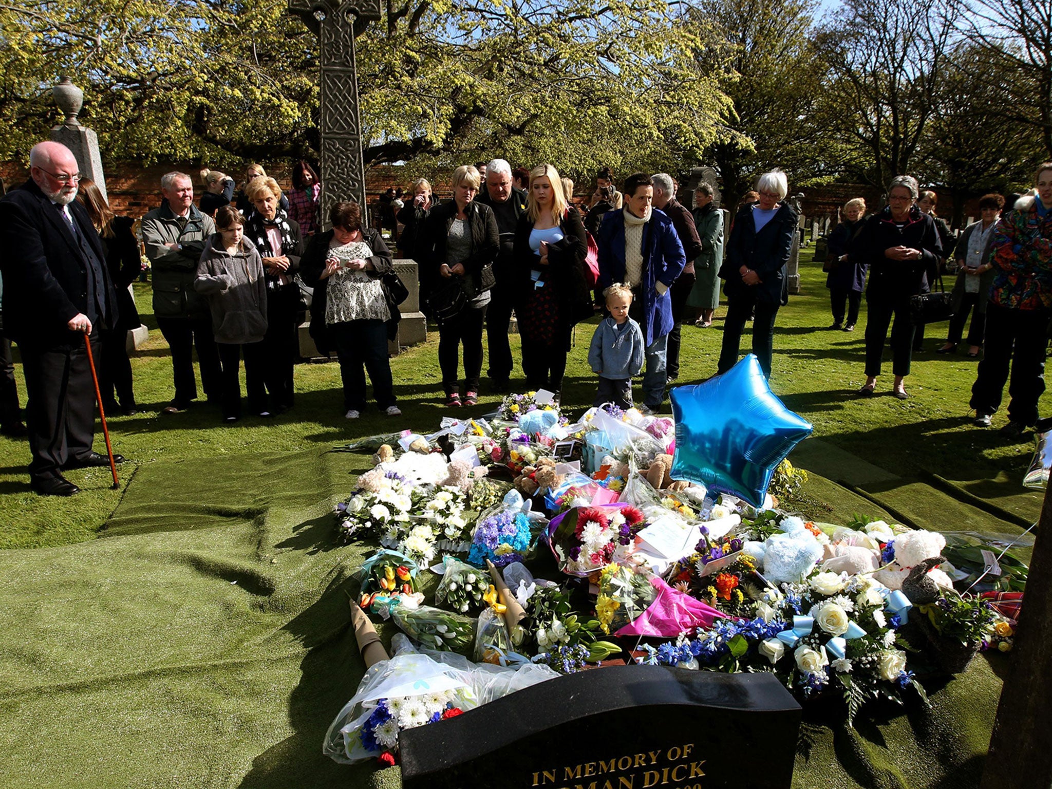 Members of the public view flowers and tributes at the graveside