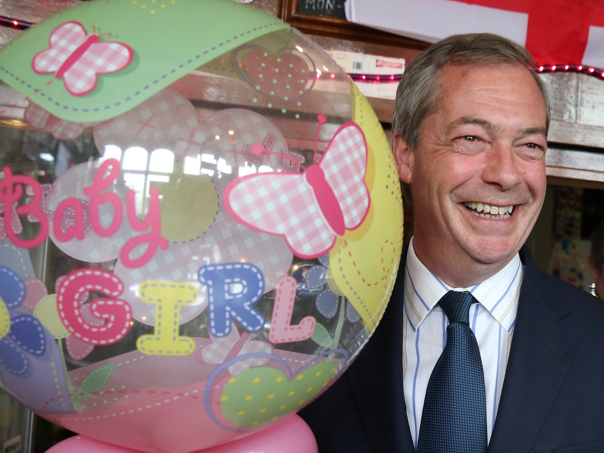 UKIP leader Nigel Farage celebrates the arrival of the new royal baby with a 'baby Girl' balloon in a pub