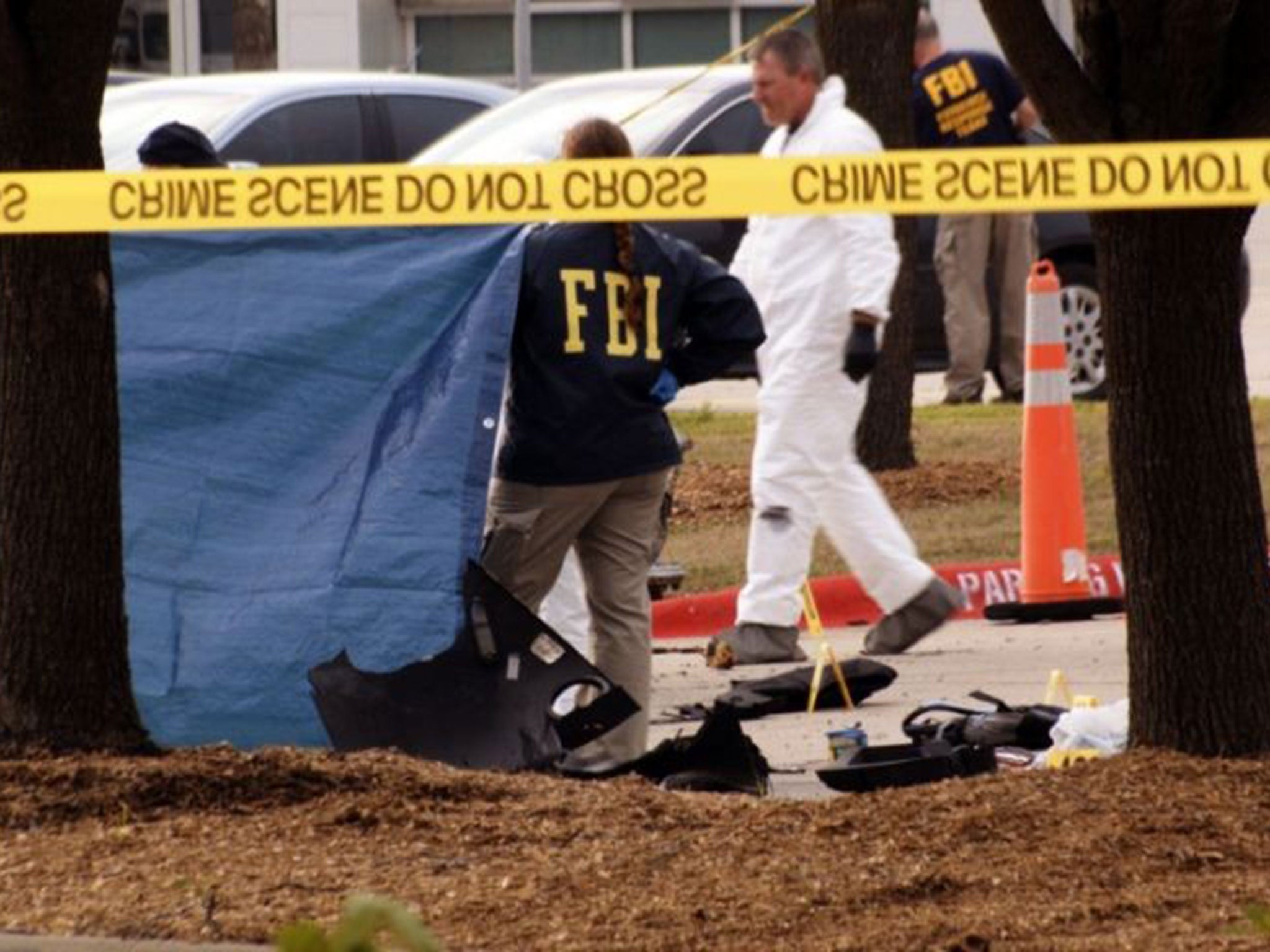 FBI agents view the area where the shooting suspects lay behind a blue covering.