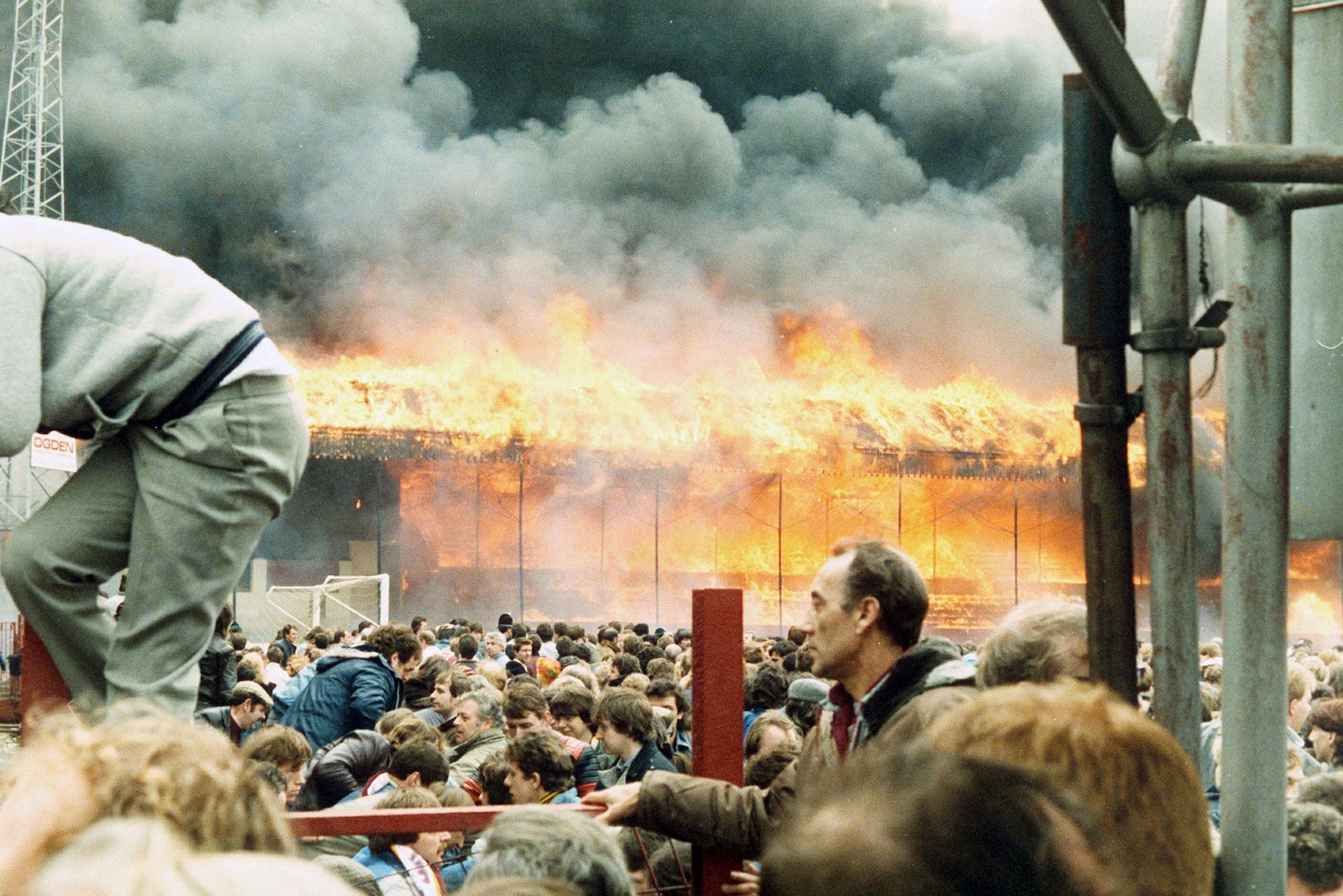 Fans flee to the pitch to avoid the flames in the wooden main stand