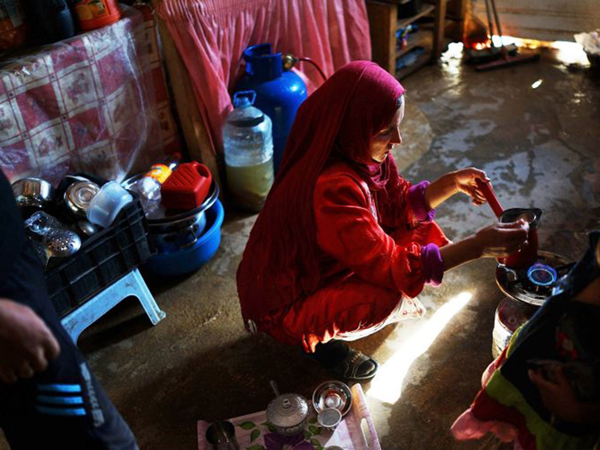 A woman from the city of Homs makes coffee in her makeshift tent home