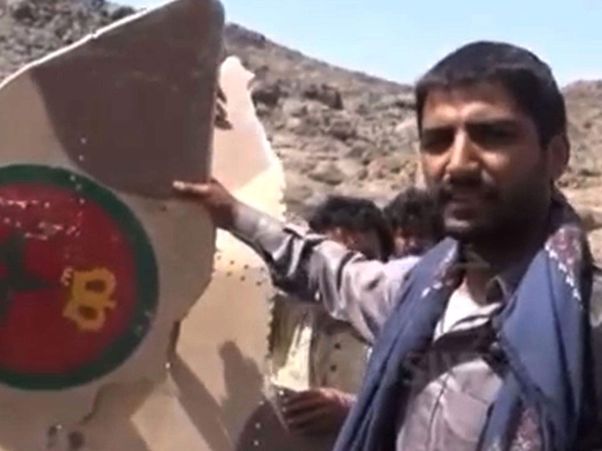 An image taken from the Huthi rebel television station Al-Masira shows Yemeni tribesmen celebrating around the wreckage of a plane bearing a Moroccan flag, in the the Wadi Nushur area in the north Yemen's province of Saada