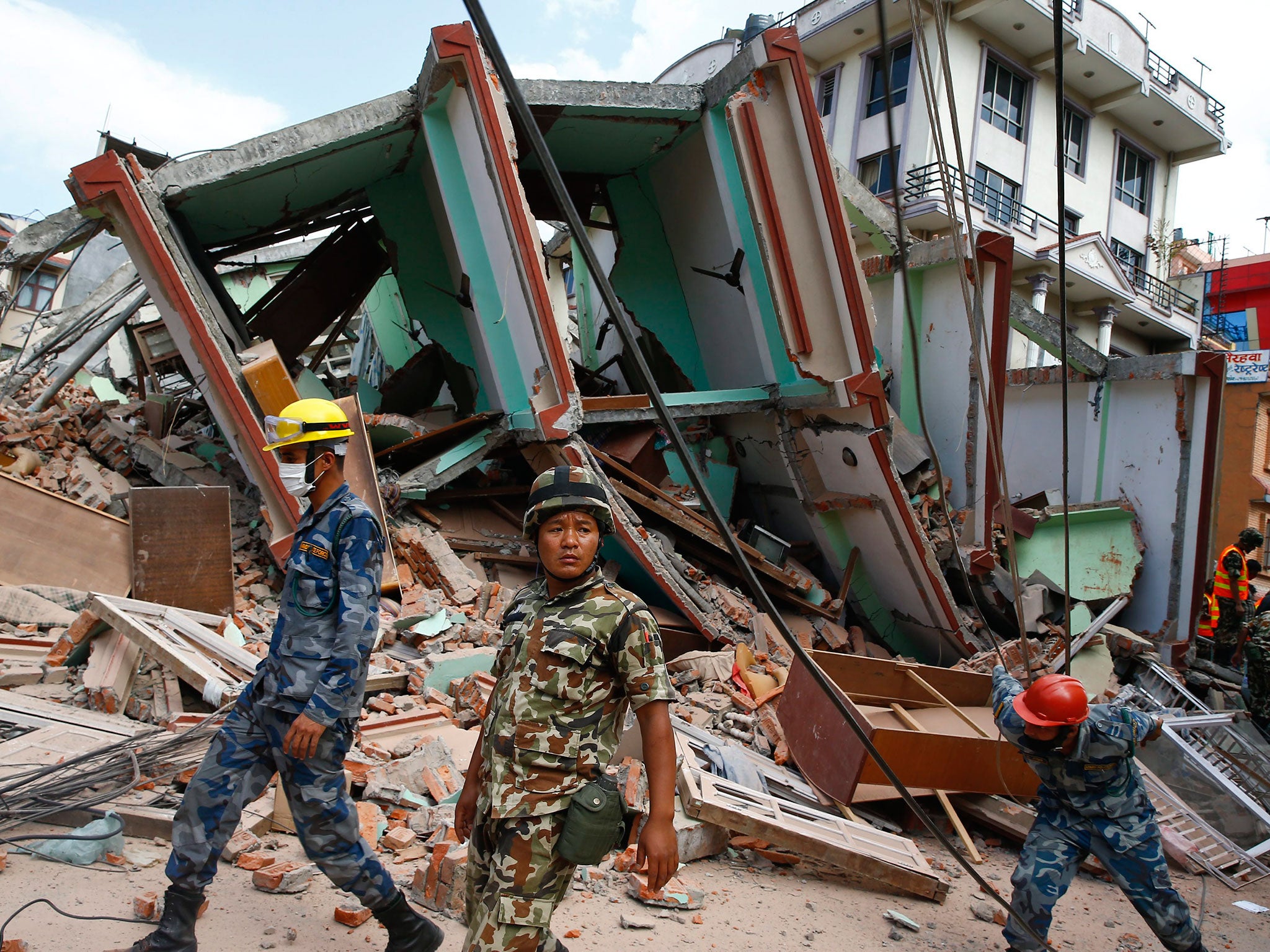 Nepalese rescue workers at the site after a house collapsed during a strong earthquake, in Kathmandu