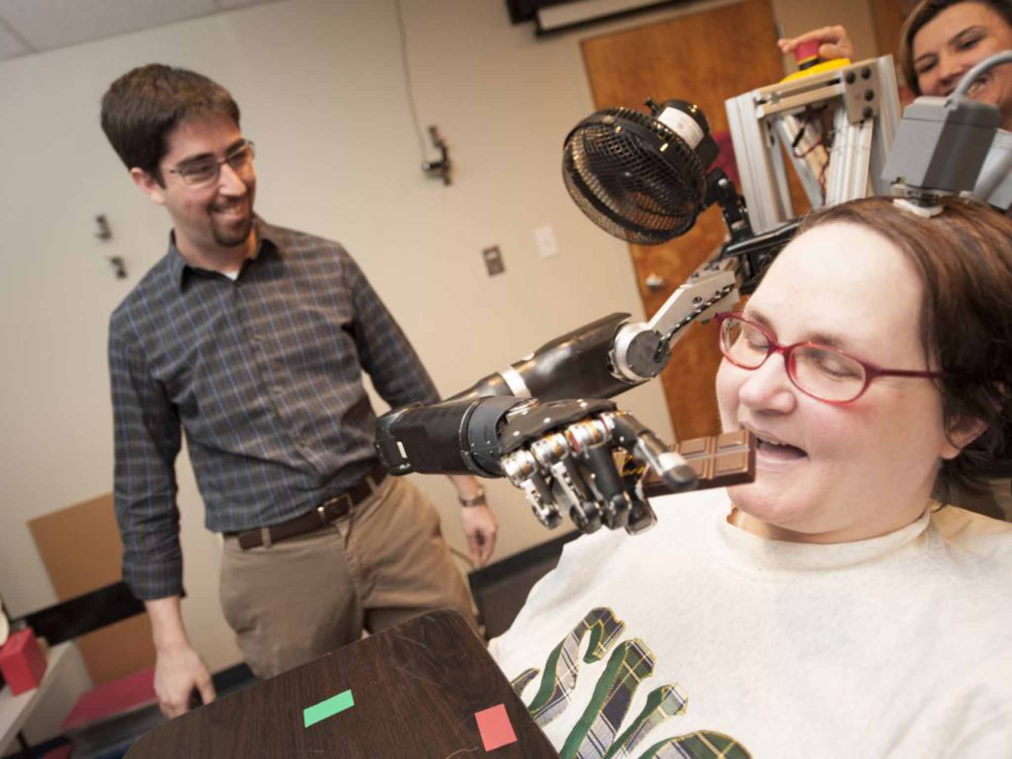 Jan Scheuermann, who has quadriplegia, reaches with a thought-controlled robot arm for a chocolate bar