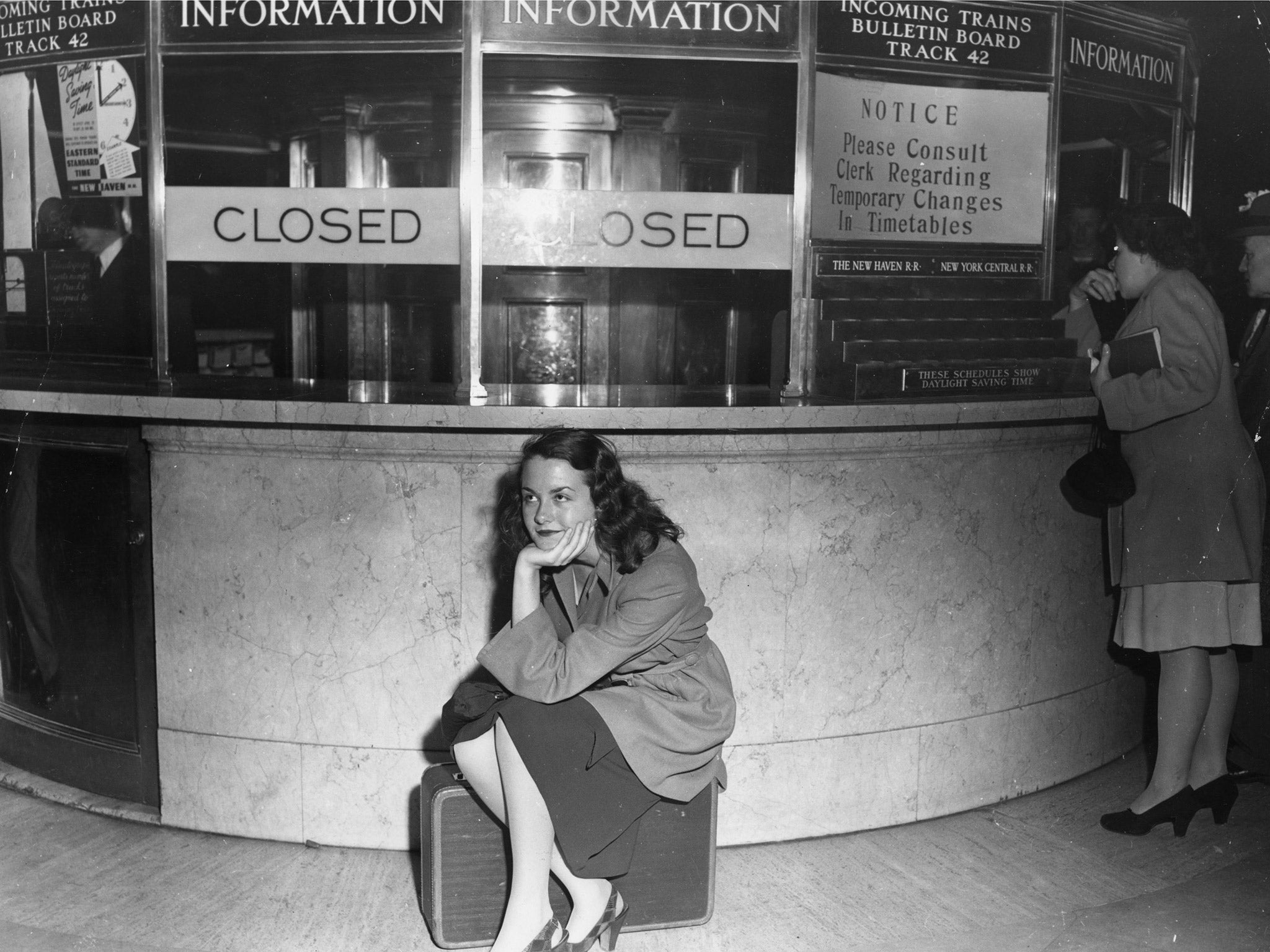 A frustrated traveller sits on her case during a rail strike, at Grand Central Station, New York, in 1946 (Getty)