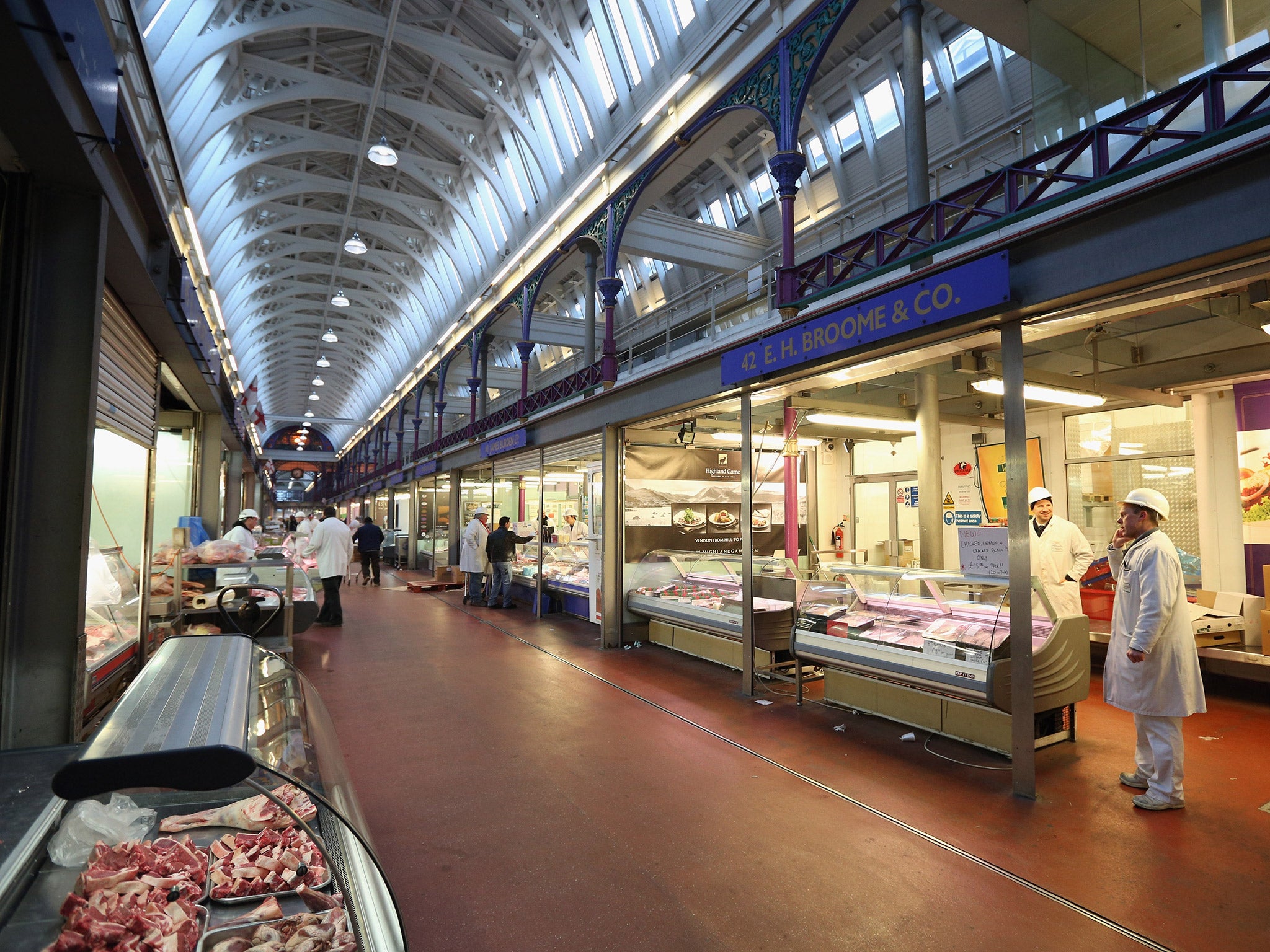 Traders and shoppers walk past butchers stalls in Smithfield Market in London