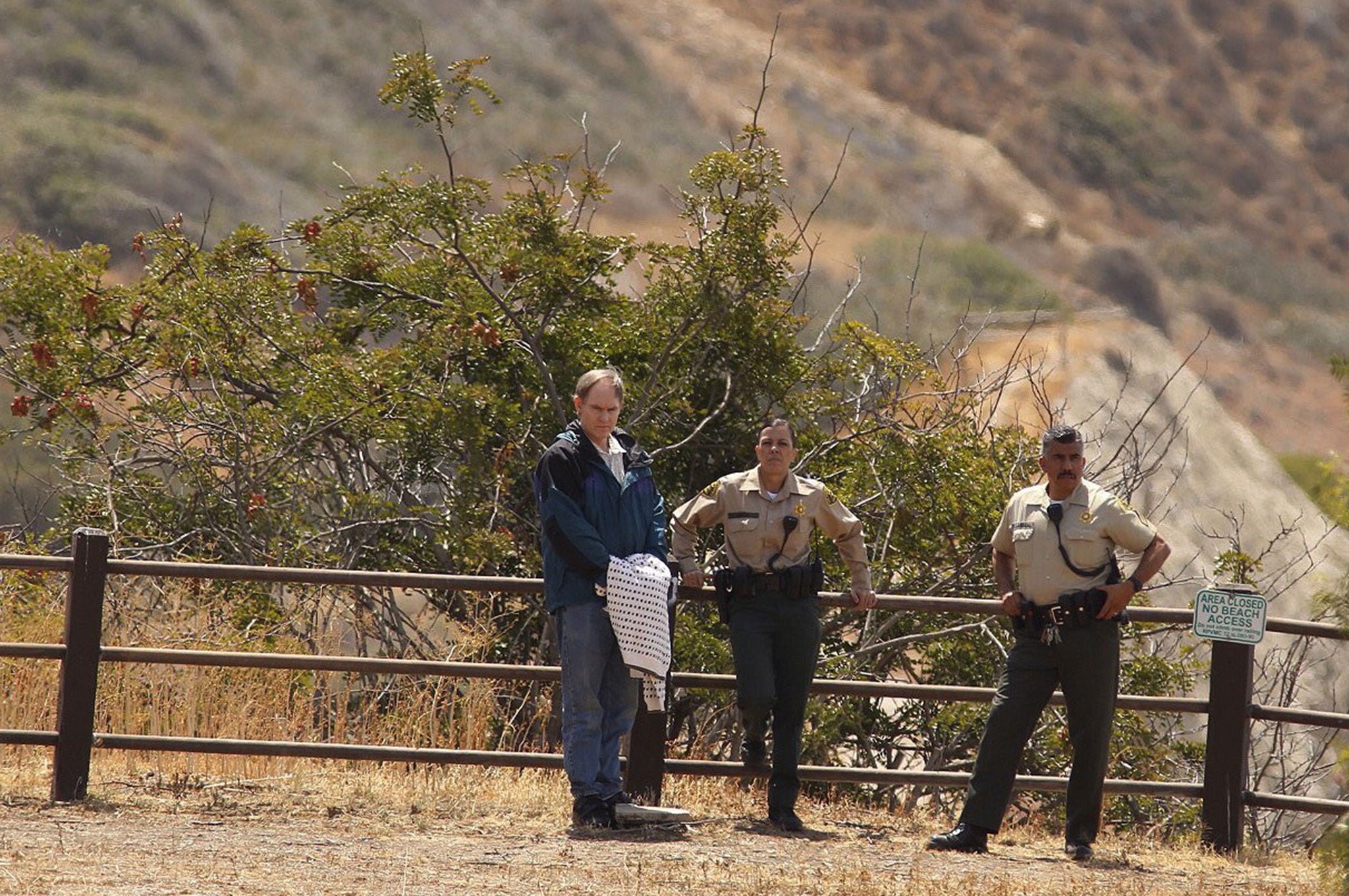 Defendent Cameron Brown (L), escorted by LA County sheriff deputies, watches as jurors make a site visit to the Abalone Cove and Portuguese Bend areas in Rancho Palos Verdes, California