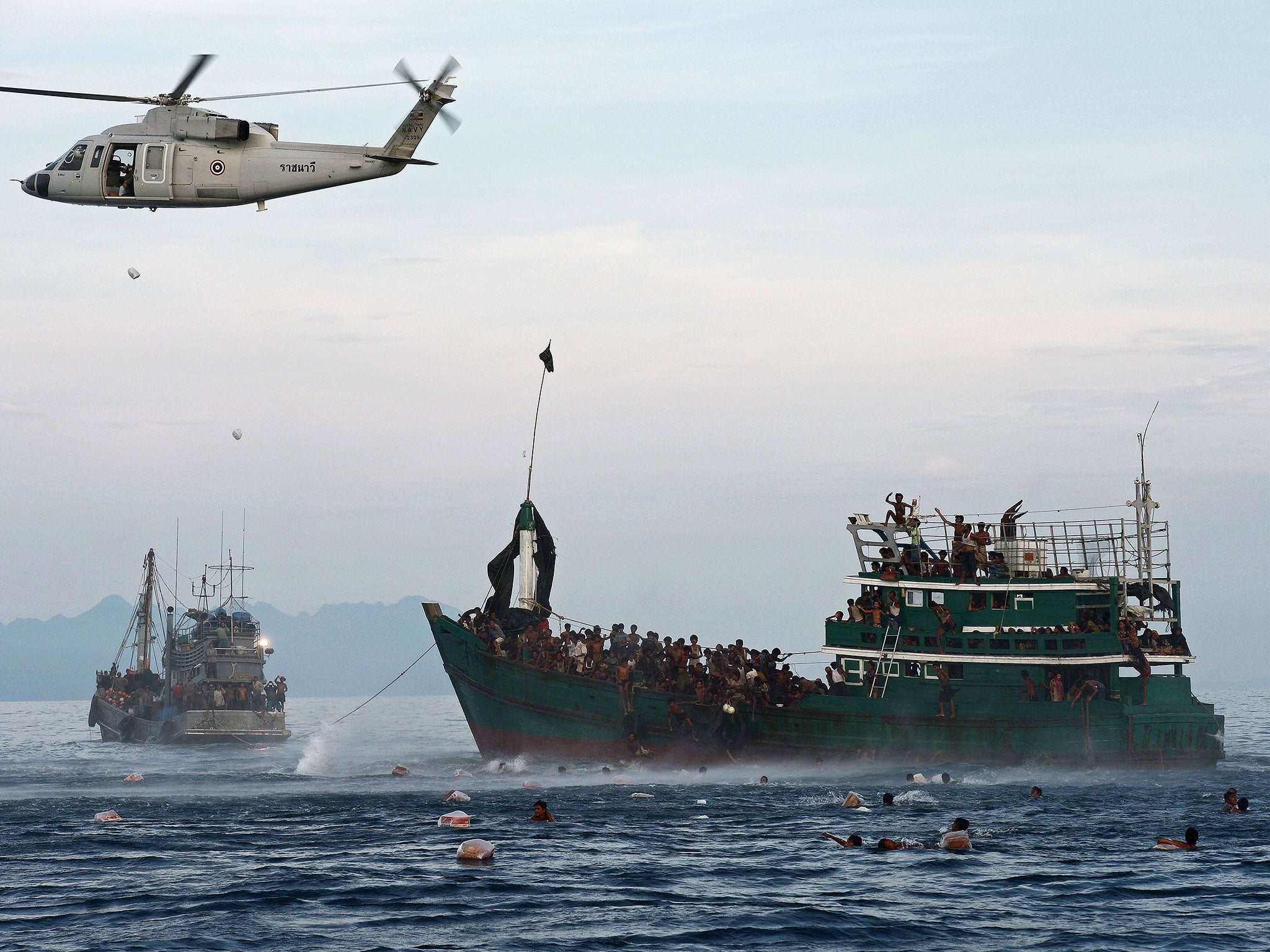 Rohingya migrants swim to collect food supplies dropped by a Thai army helicopter