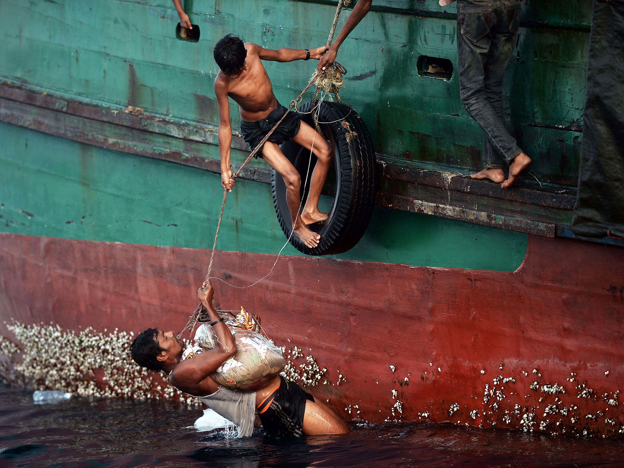 Rohingya migrants bring back food supplies dropped by a Thai army helicopter