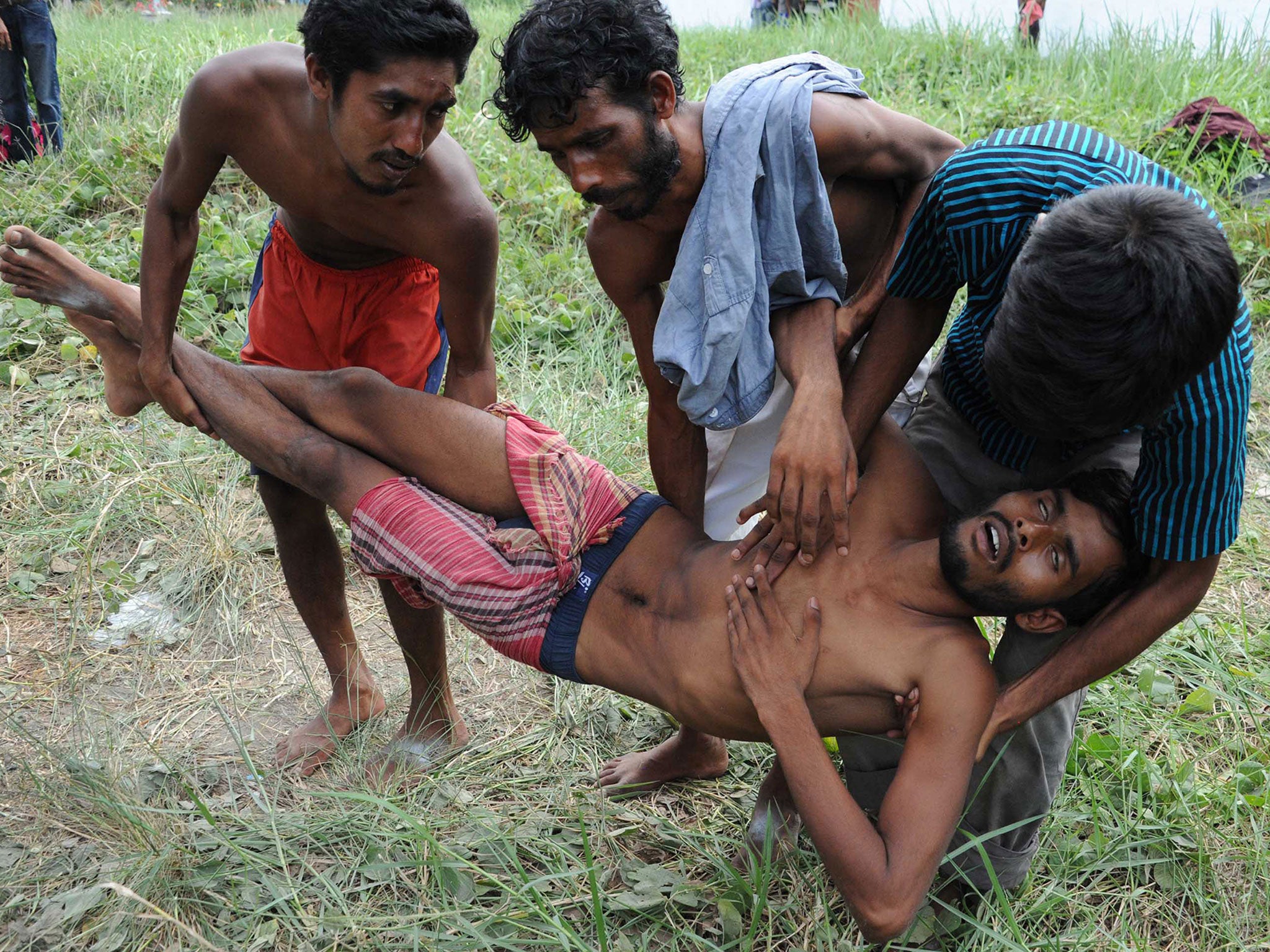 A sick rescued migrant is assisted by other migrants on their arrival at the new confinement area in the fishing town of Kuala Langsa in Aceh province