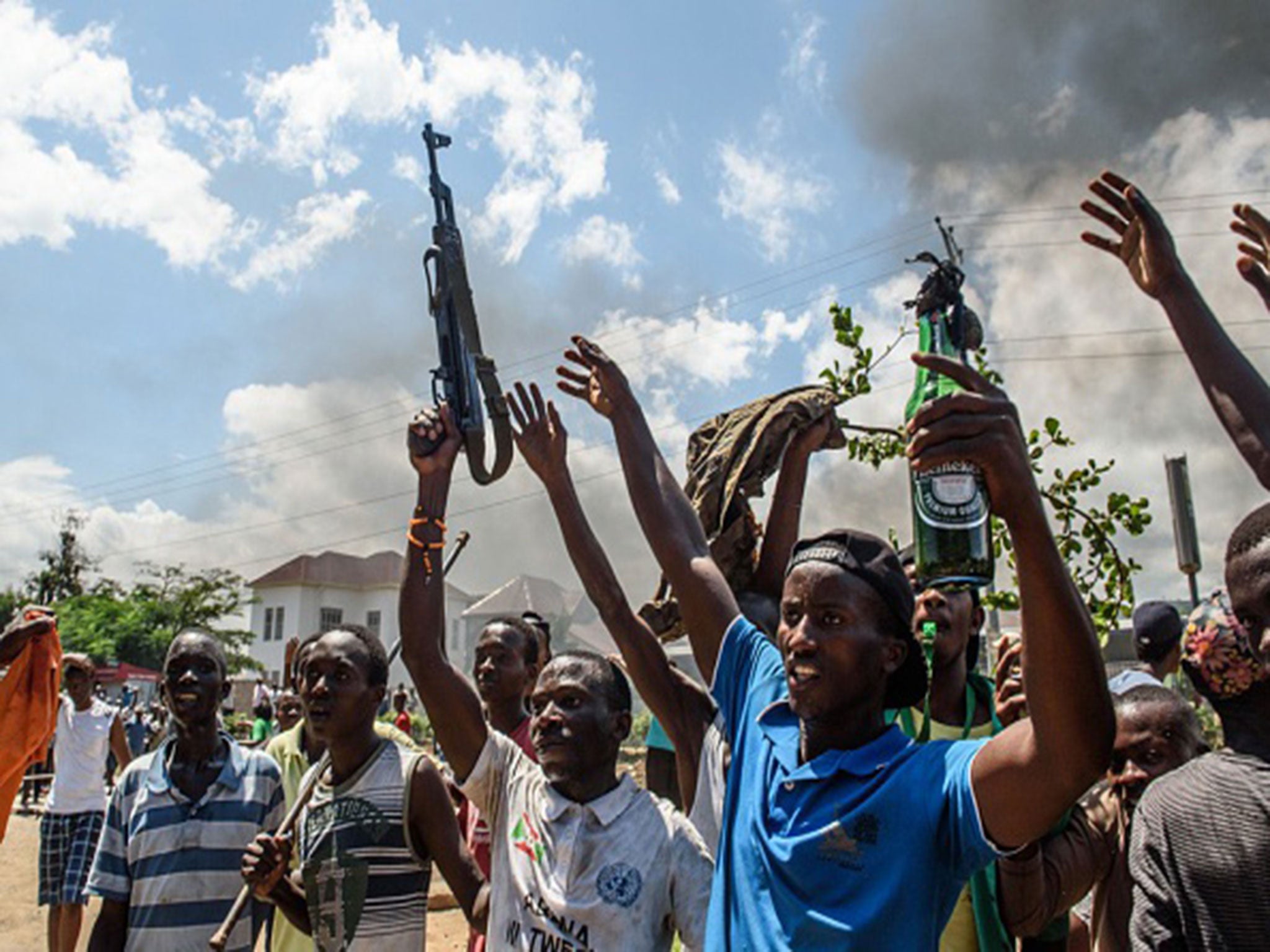 A man holding a gun taken from a police officer and a man holding a molotov cocktail gesture after heavy clashes with police