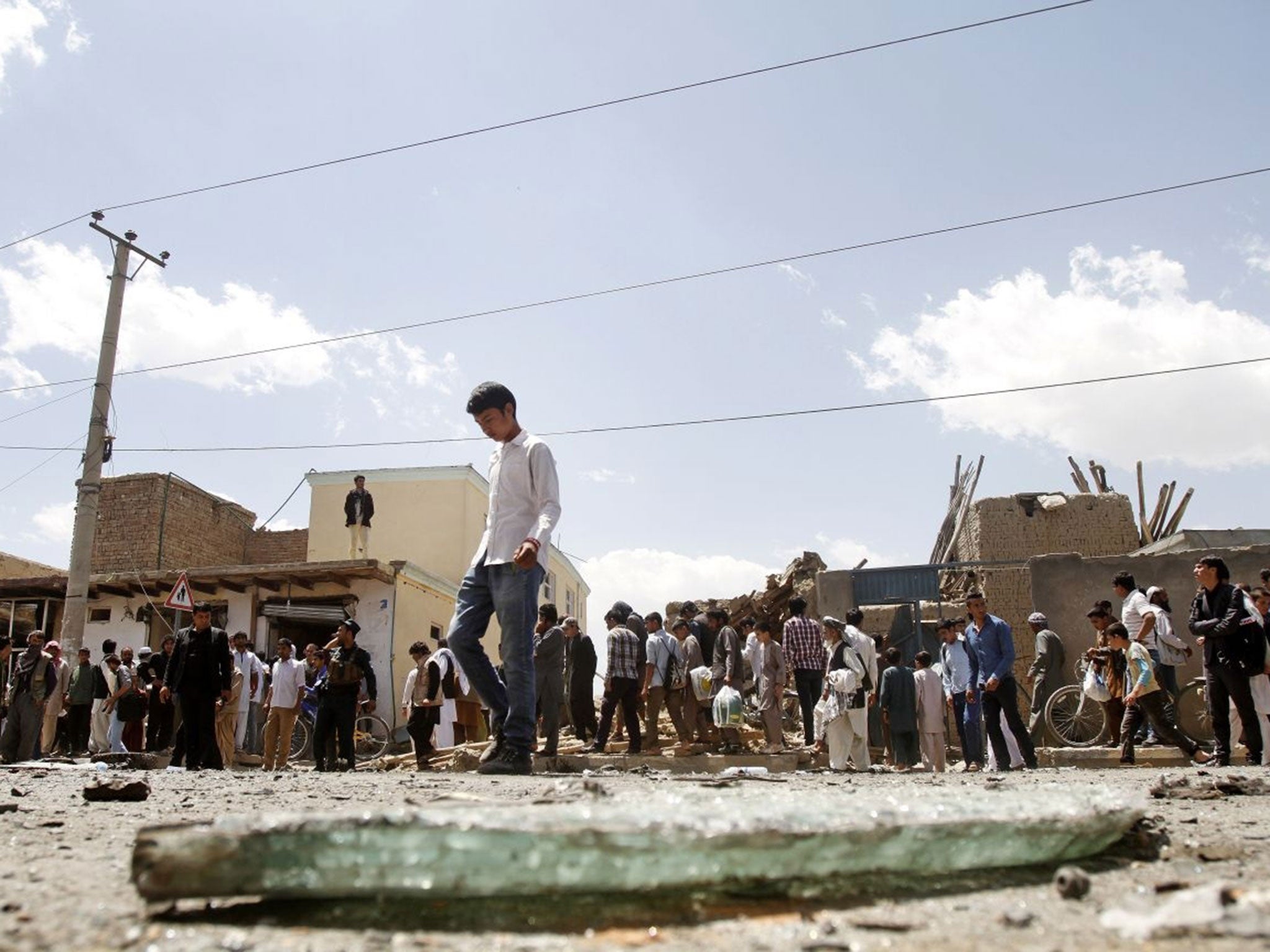 Afghans inspect the site of a suicide attack near Kabul's international airport in Afghanistan, Sunday, May 17, 2015. A suicide bomber detonated an explosives-packed car near Kabul's international airport on Sunday, wounding at least 16 civilians in an at