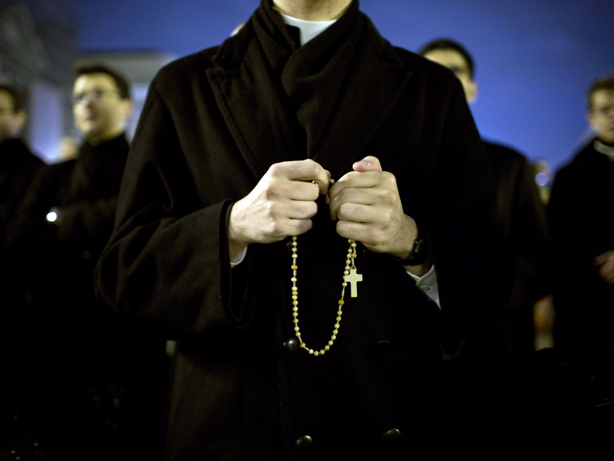 Priests pray in front of St Peter's Basilica in St. Peter's Square