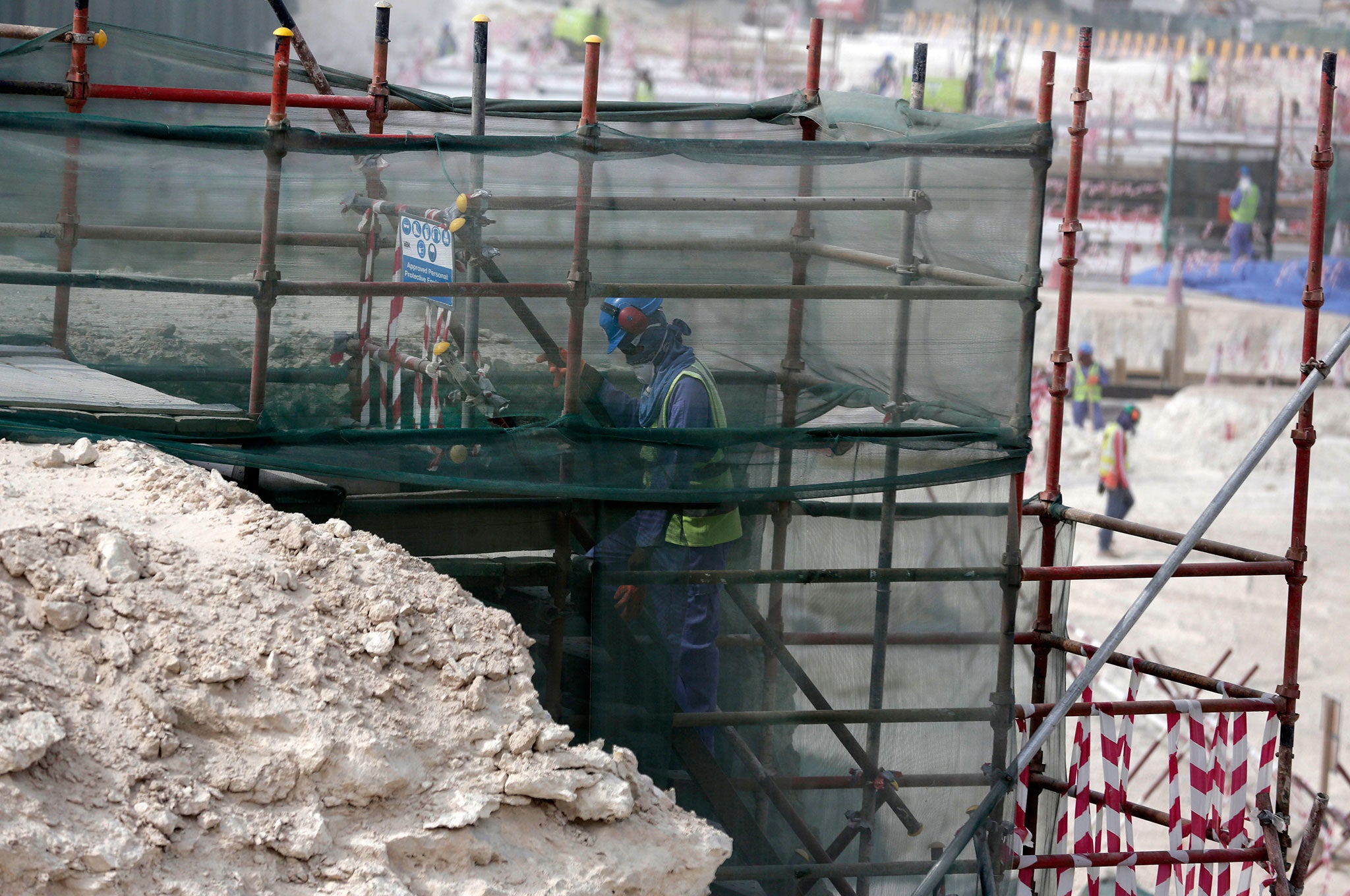 A foreign worker climbs scaffolding at the Al-Wakra Stadium that is under construction for the 2022 World Cup in Doha, Qatar