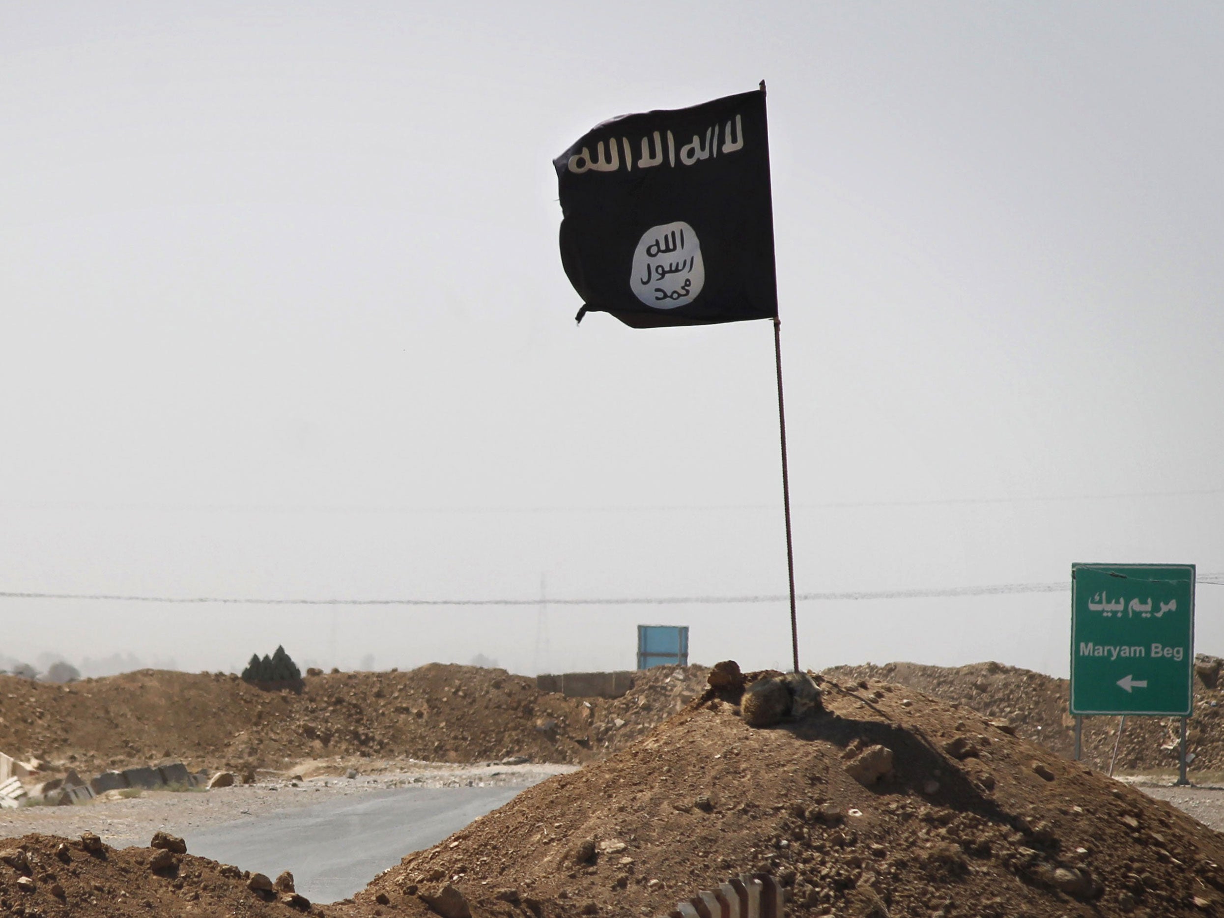 A flag of the Islamic State (IS) is seen on the other side of a bridge at the frontline of fighting between Kurdish Peshmerga fighters and Islamist militants in Rashad, on the road between Kirkuk and Tikrit, on September 11, 2014.