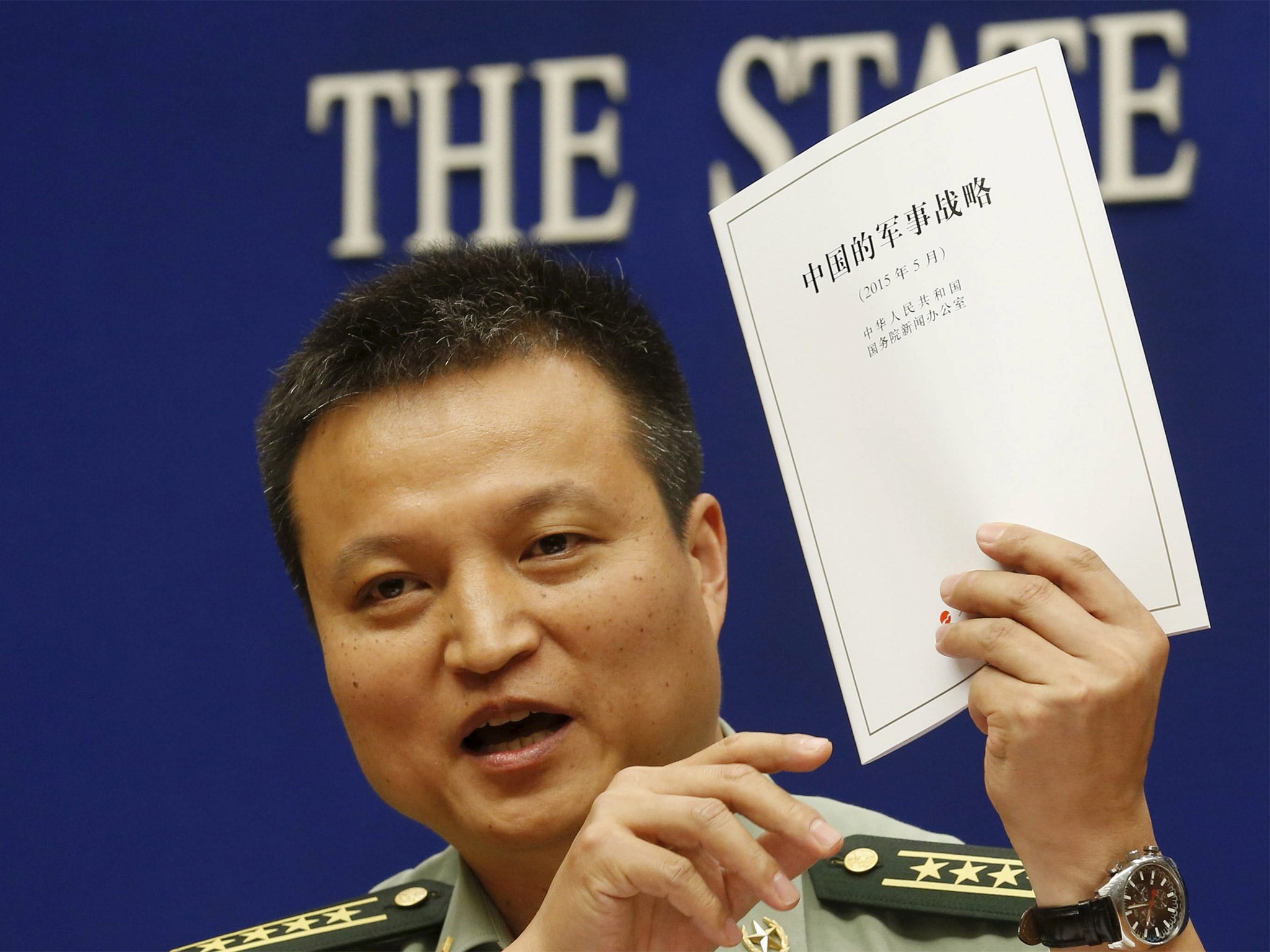 People’s Liberation Army spokesman Yang Yujun holds a copy of the annual white paper during a news conference in Beijing