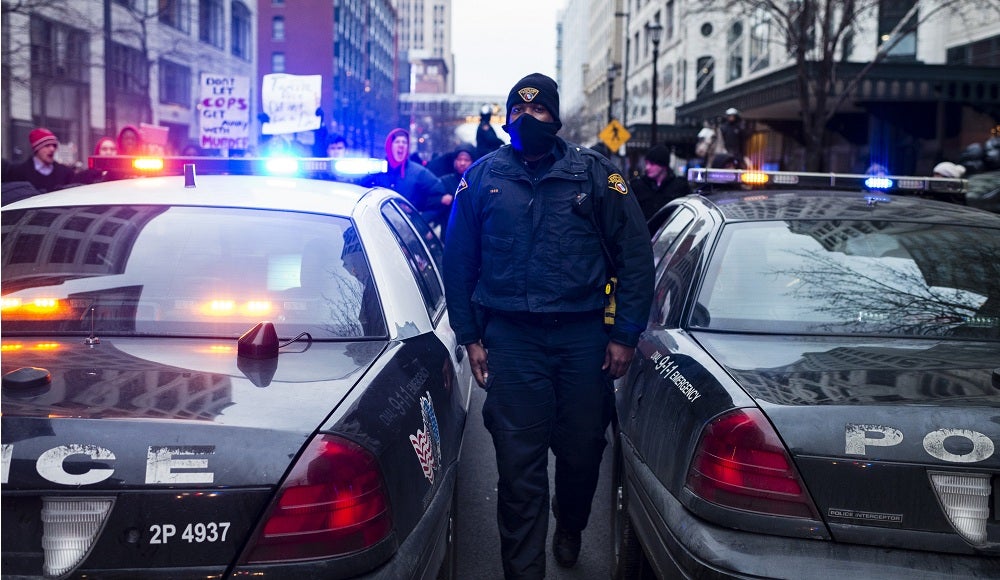 An unidentified Cleveland Police Office walks between cars on Ontario Street 21 December, 2014.