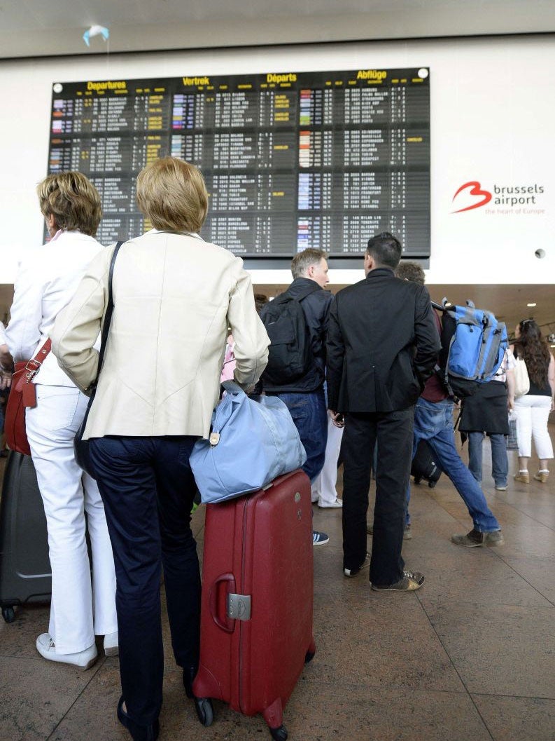 People look at an information board displaying delayed and canceled flights at Brussels airport