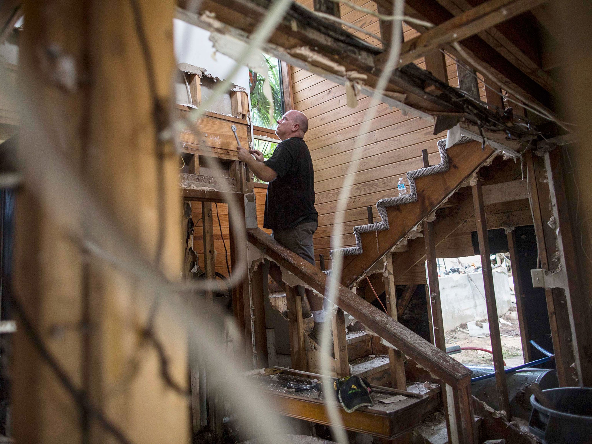 Michael Fisher strips drywall from his mother-in-law's flood damaged home in Wimberley